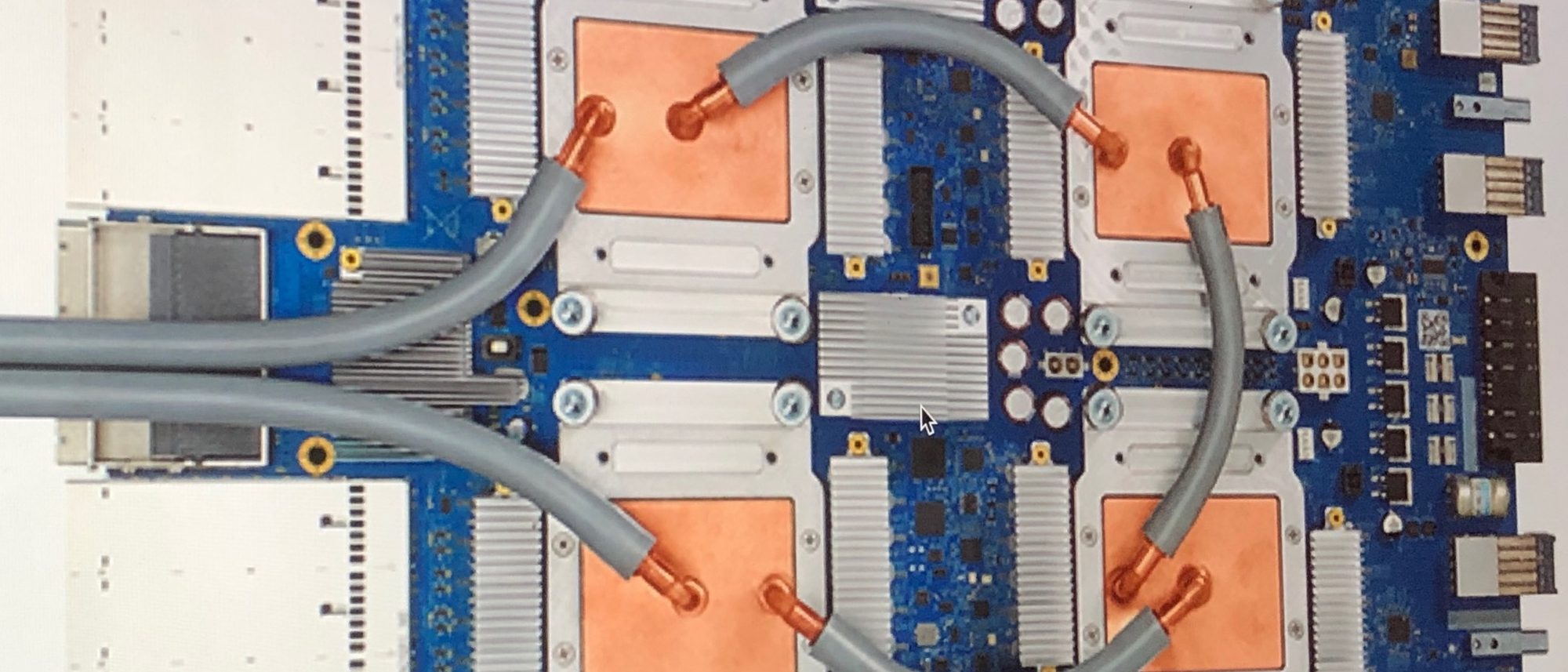 A Google Tensor Processing Unit 3.0 board: four copper-capped chips joined by grey cooling tubes on a blue circuit board