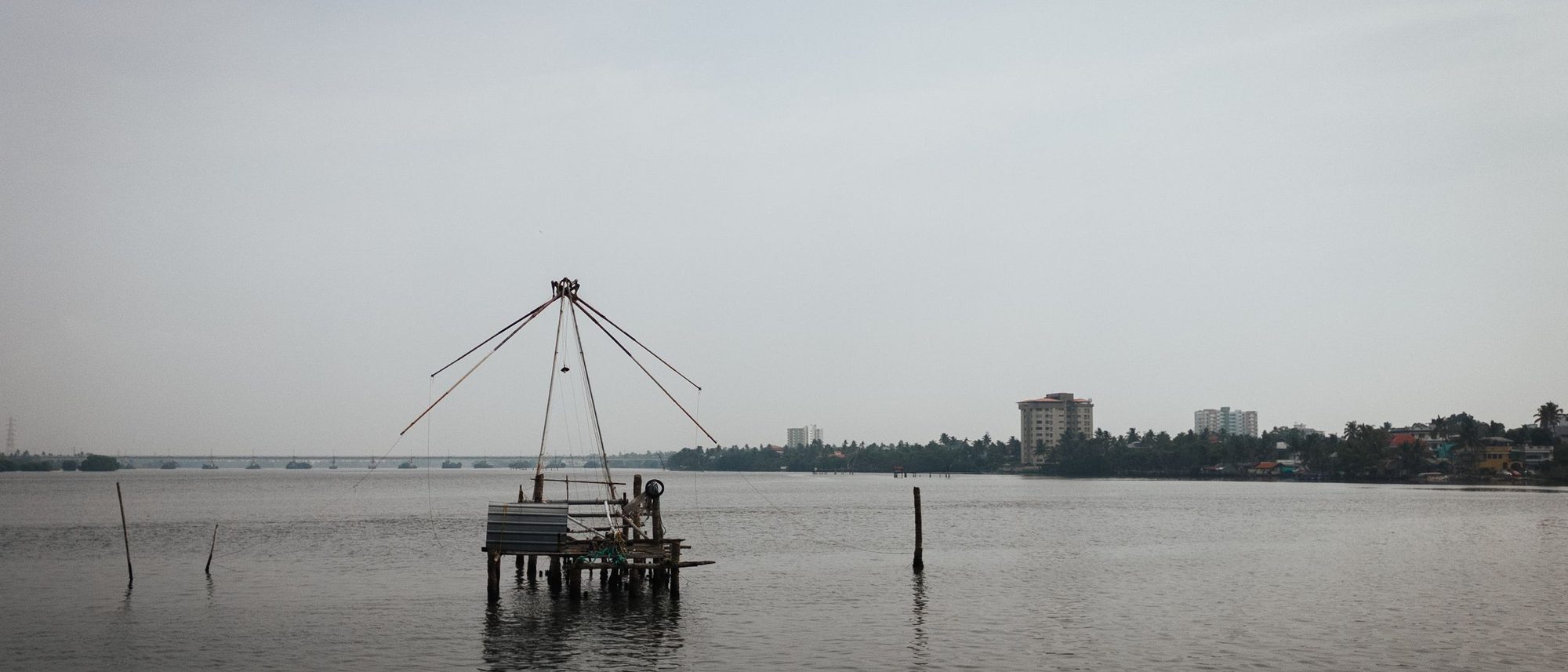 A shore-operated lift net hangs over the water on the Kochi coastline.