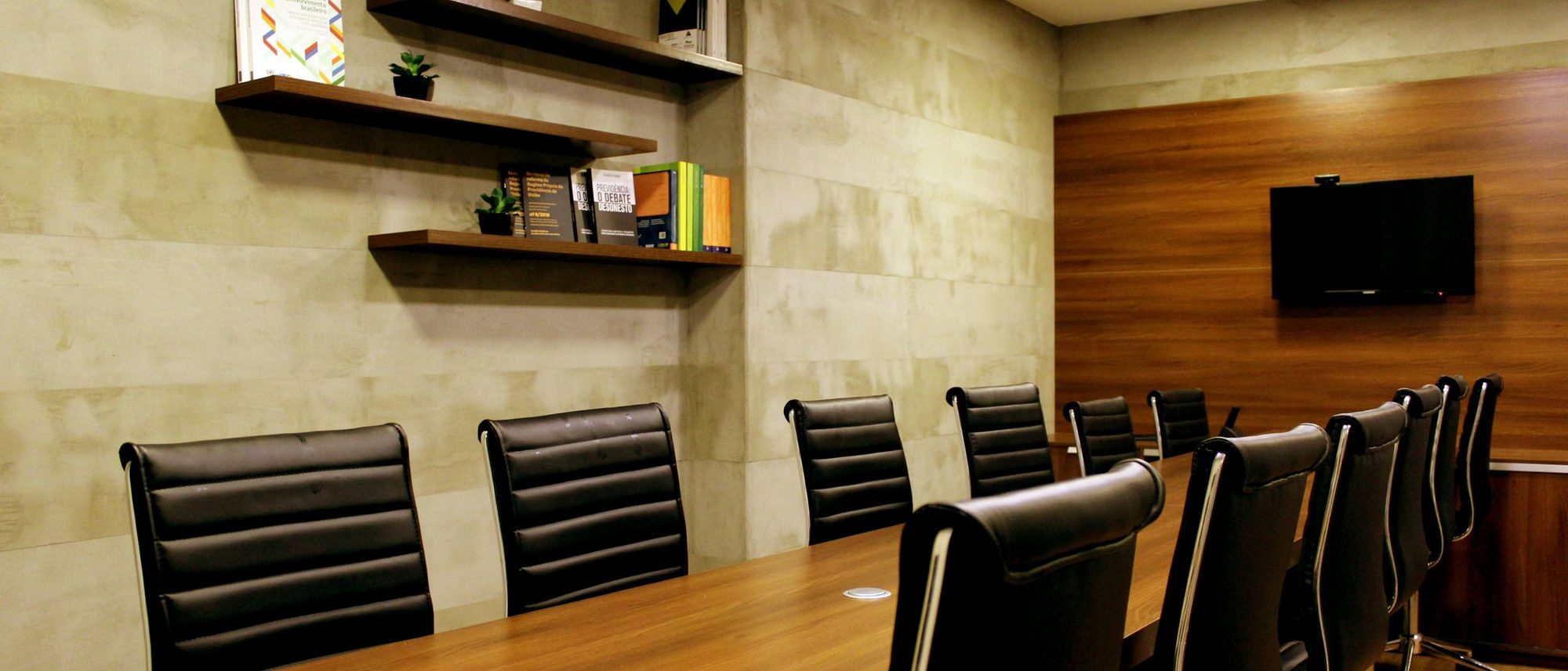 Black leather chairs around a boardroom table in a wood-panelled room.