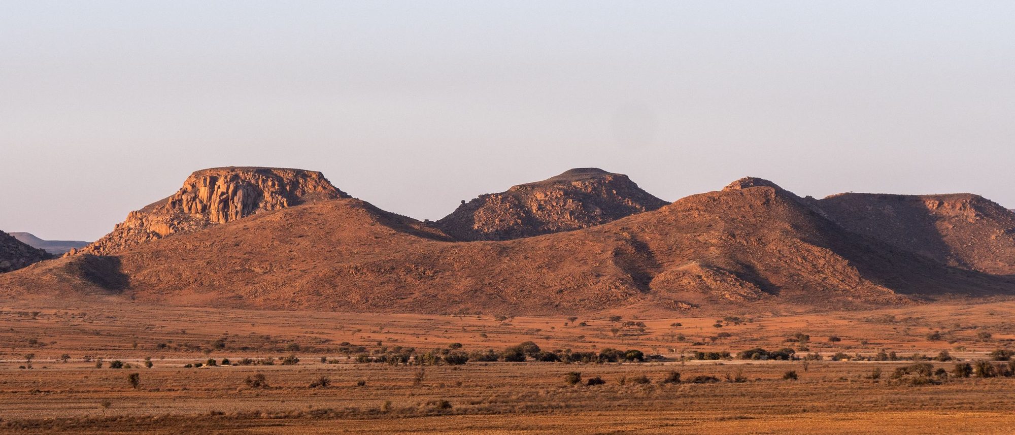 Flat-topped rocky plateaus stretch to the horizon under a sunset sky in South Africa.