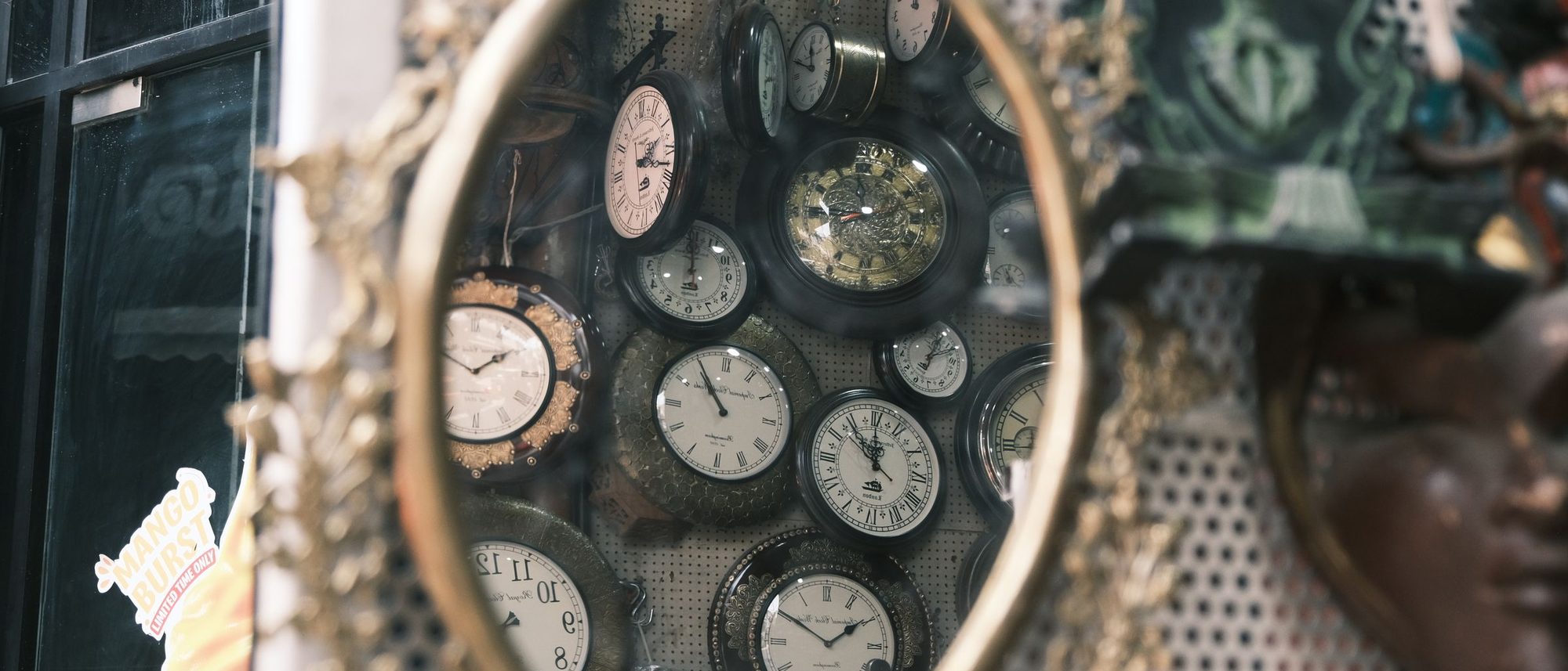 A collection of vintage clocks reflected in an ornate antique mirror in Bengaluru.