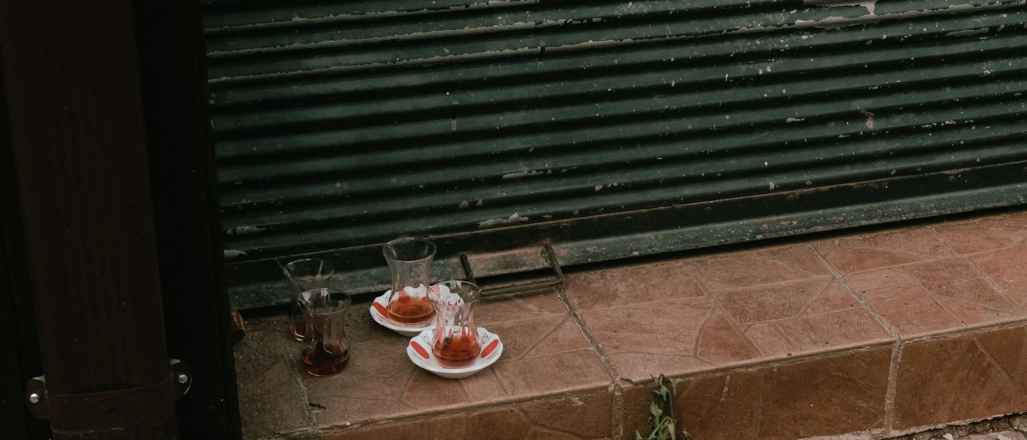 Empty tea glasses left behind on a stone step in a city street.
