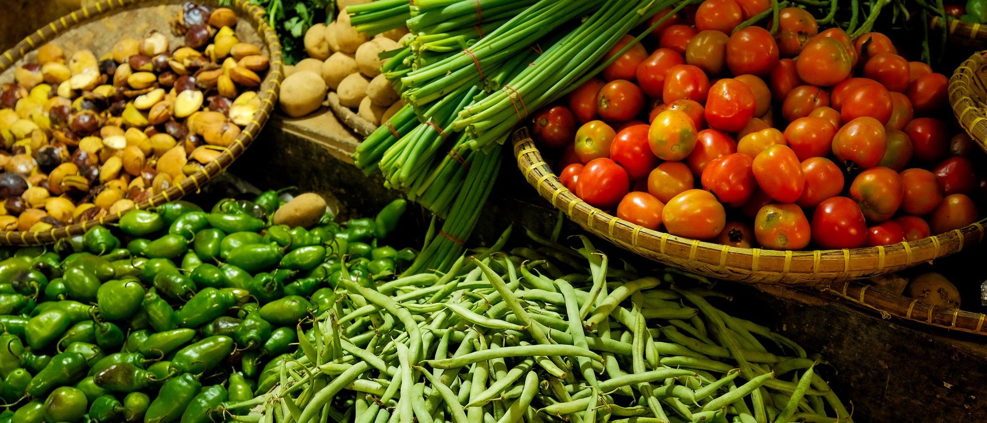 Heaps of fresh vegetables laid out side by side on a market stall.