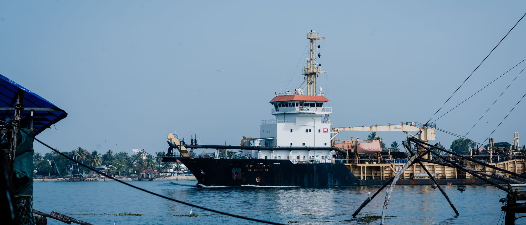 A cargo ship lies at anchor in Kochi harbour beyond the frames of the Chinese fishing nets.