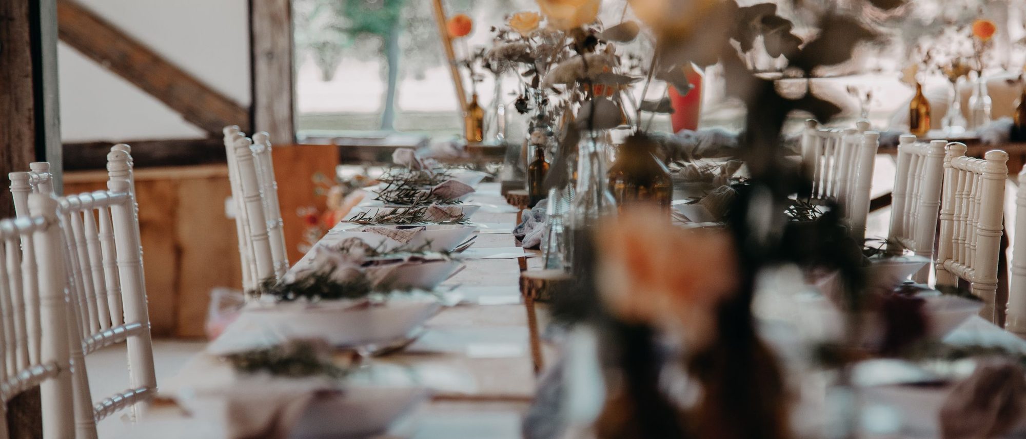 A long table laid with plates, glasses and flowers before guests arrive.