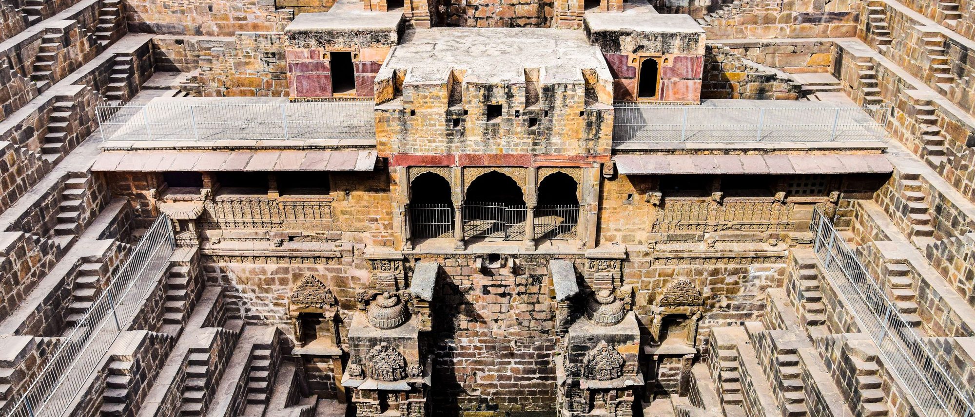 Symmetrical flights of stone steps descend into an ancient stepwell in India.