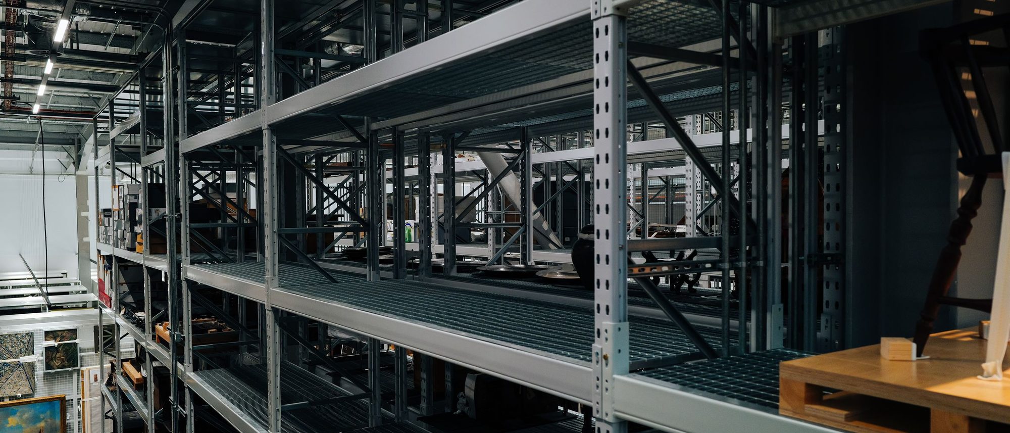 Empty metal storage racks in rows across a large industrial warehouse.