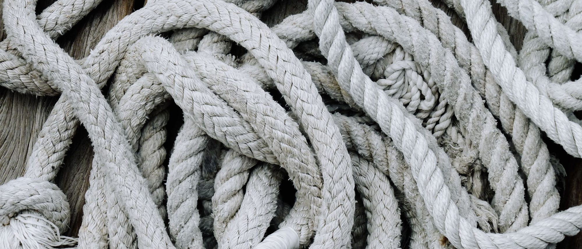 Coiled and tangled marine rope lies on a weathered wooden deck.