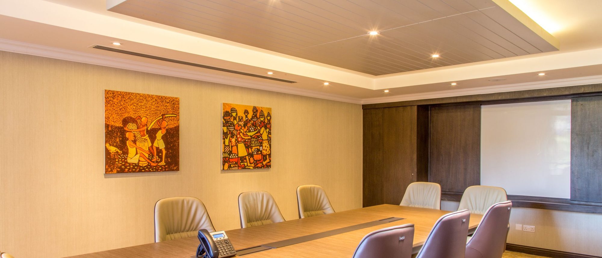 An empty conference room with a long table and chairs set around it, lit by daylight.