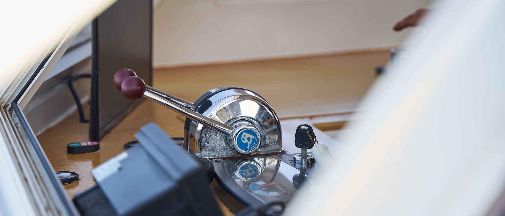 A row of polished metal control levers on a boat, with window light reflected in the steel.