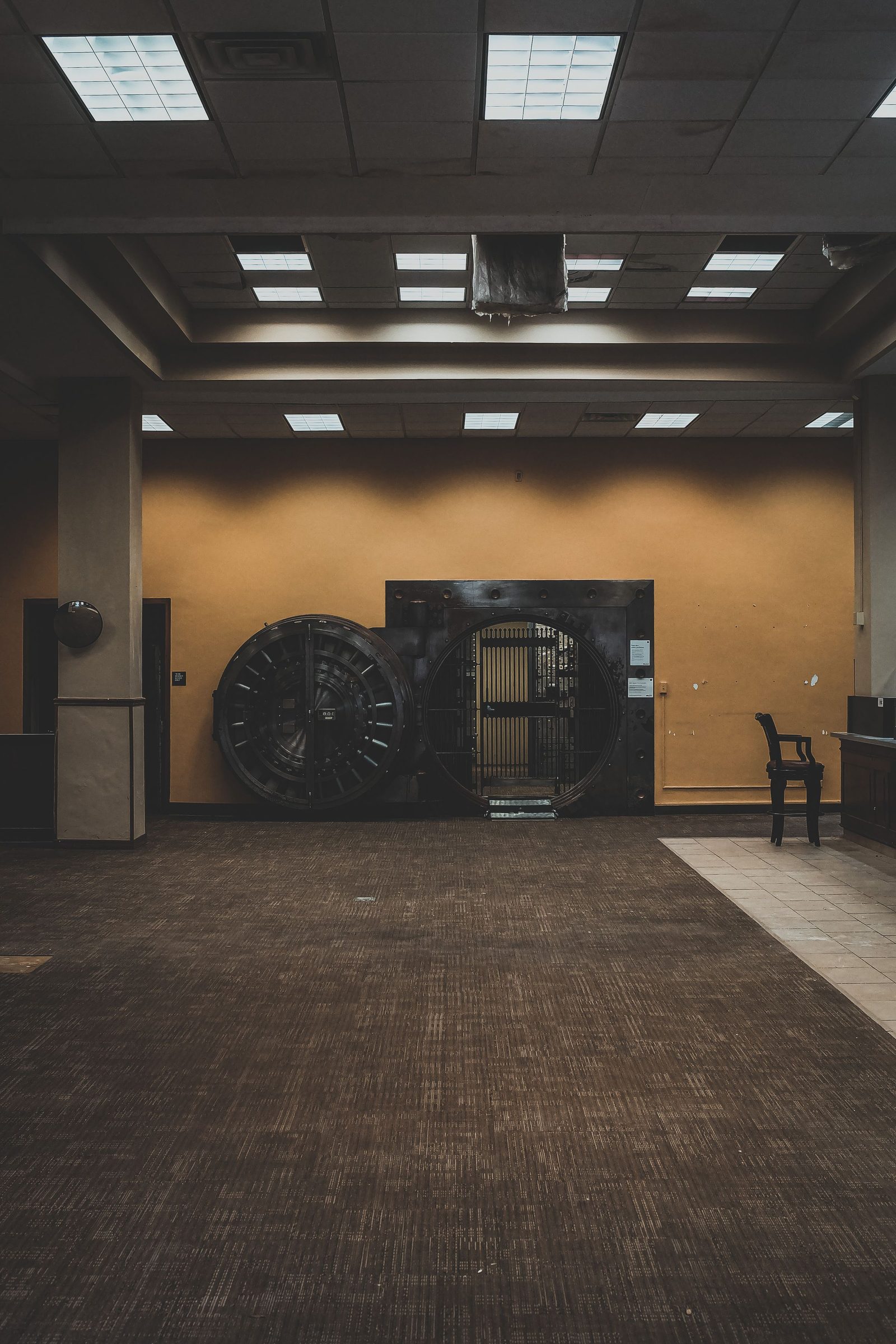 A heavy round vault door stands open inside a bank.