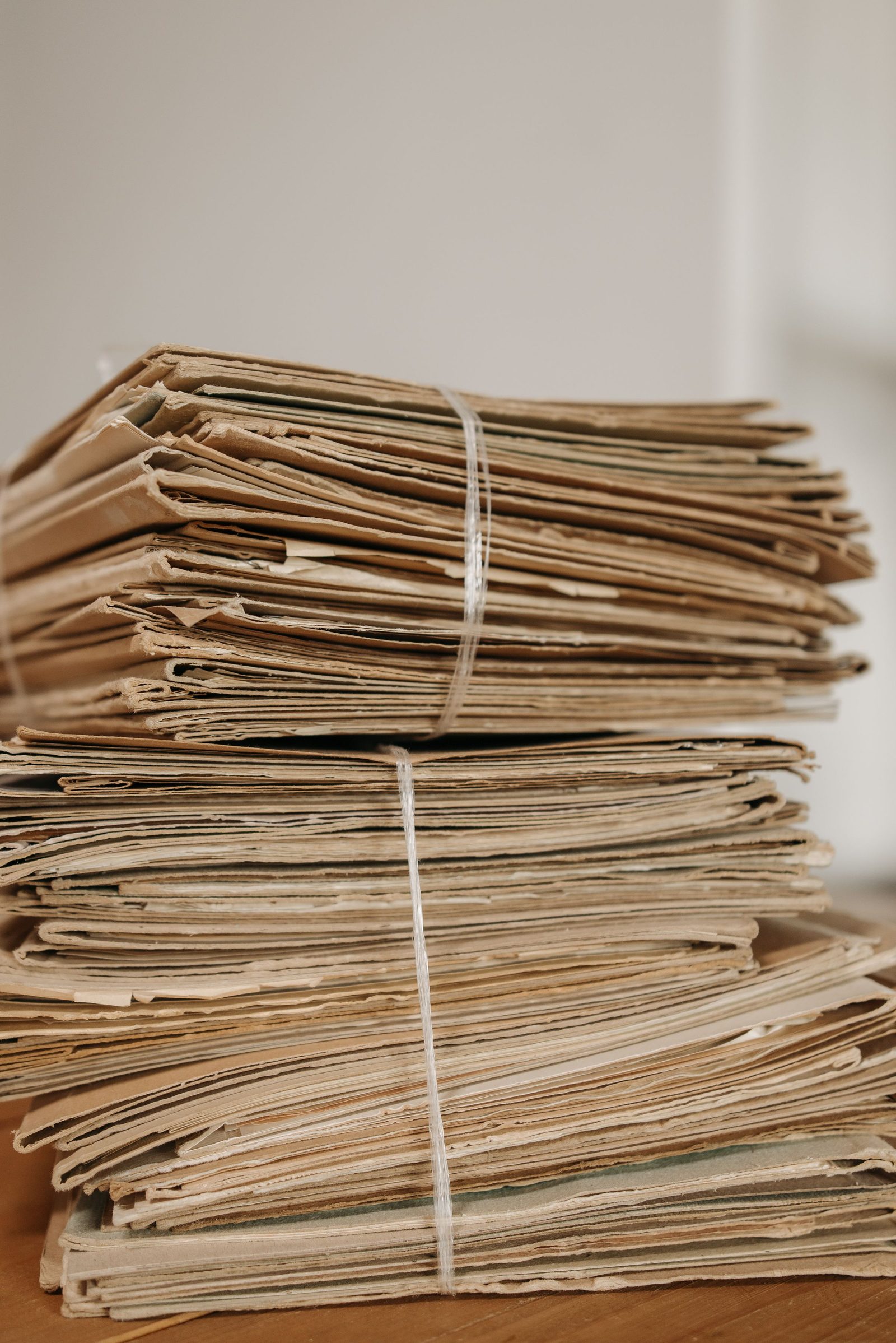 A stack of brown paper folders tied together with string on a wooden surface.