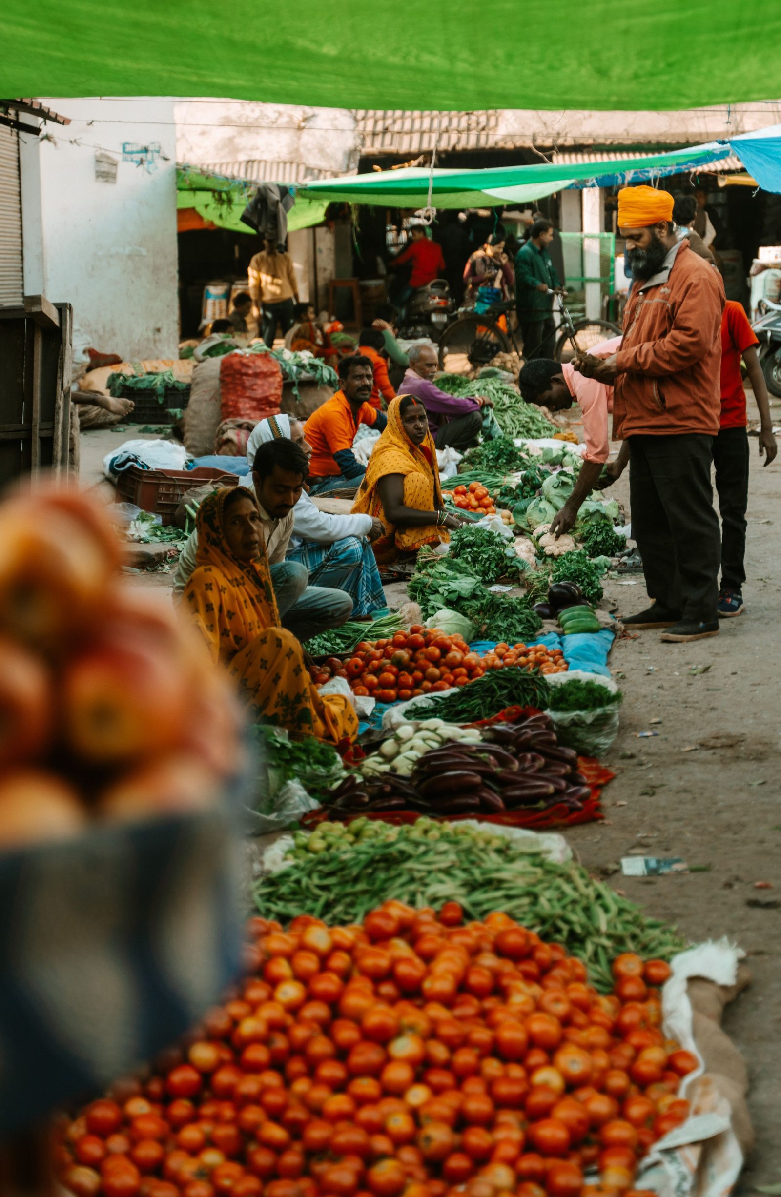 Vendors selling fresh vegetables and fruit at an outdoor market in India.