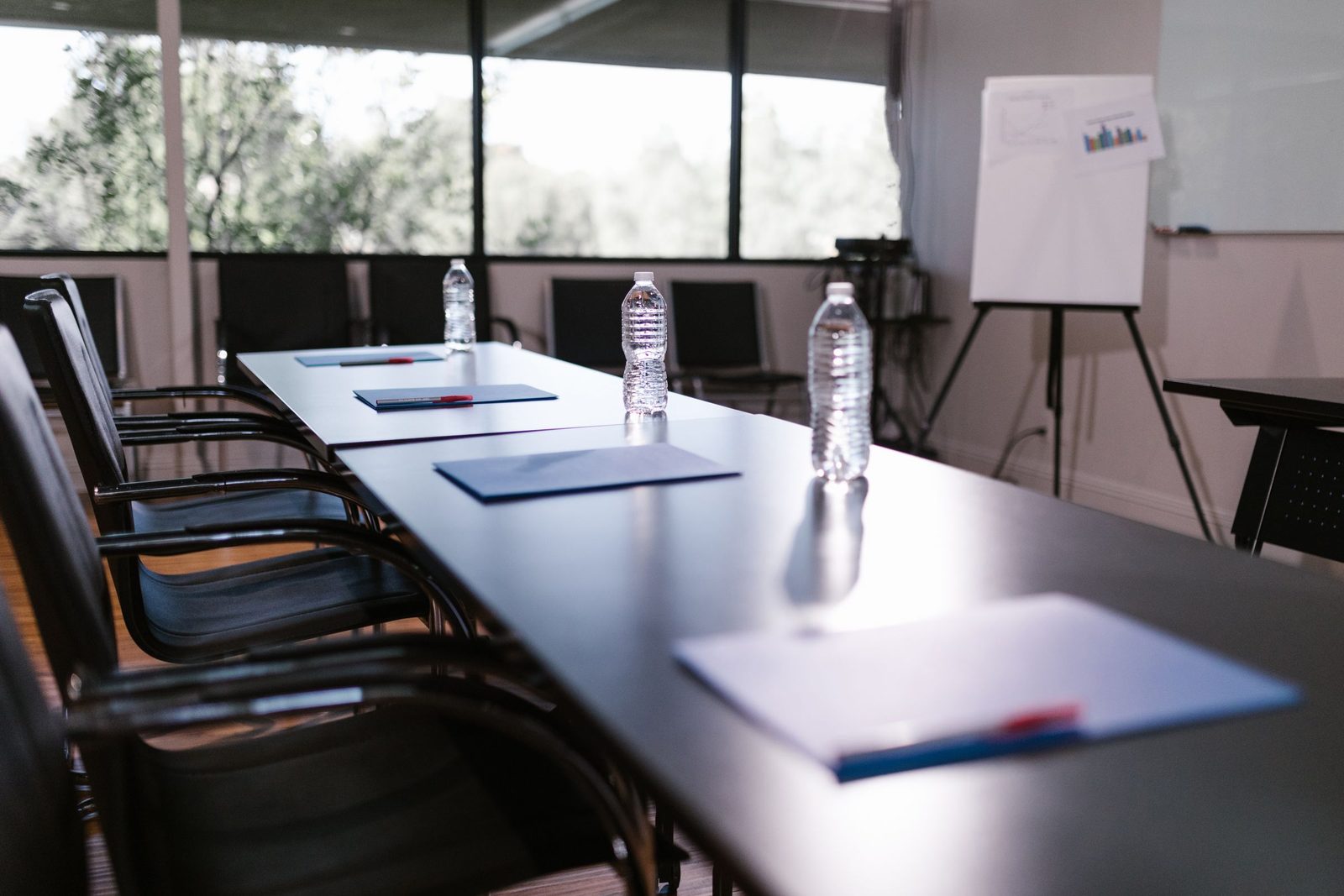 An empty conference room with water bottles and notepads set out on a long wooden table.