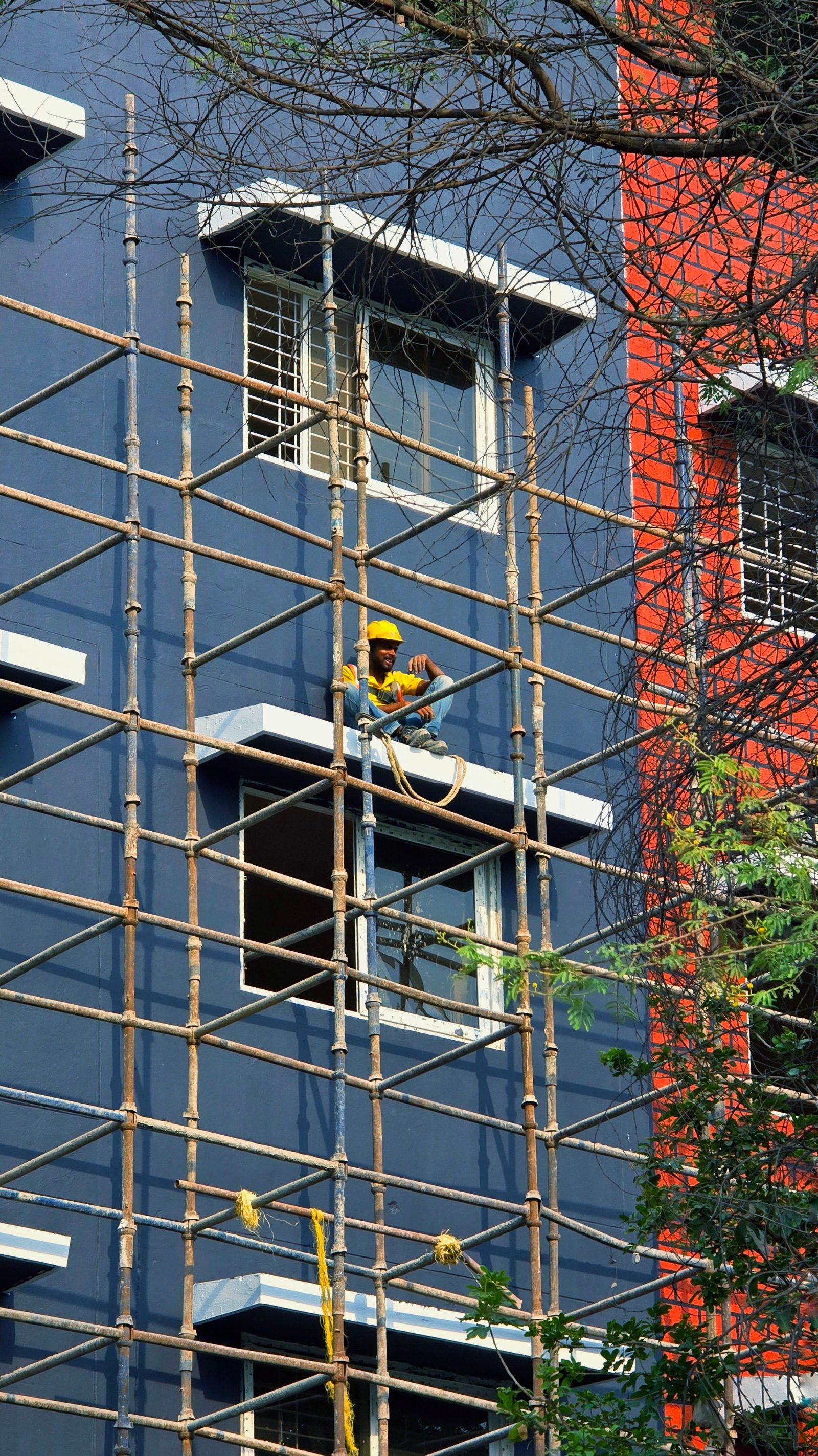 A construction worker climbs bamboo scaffolding on a building site.