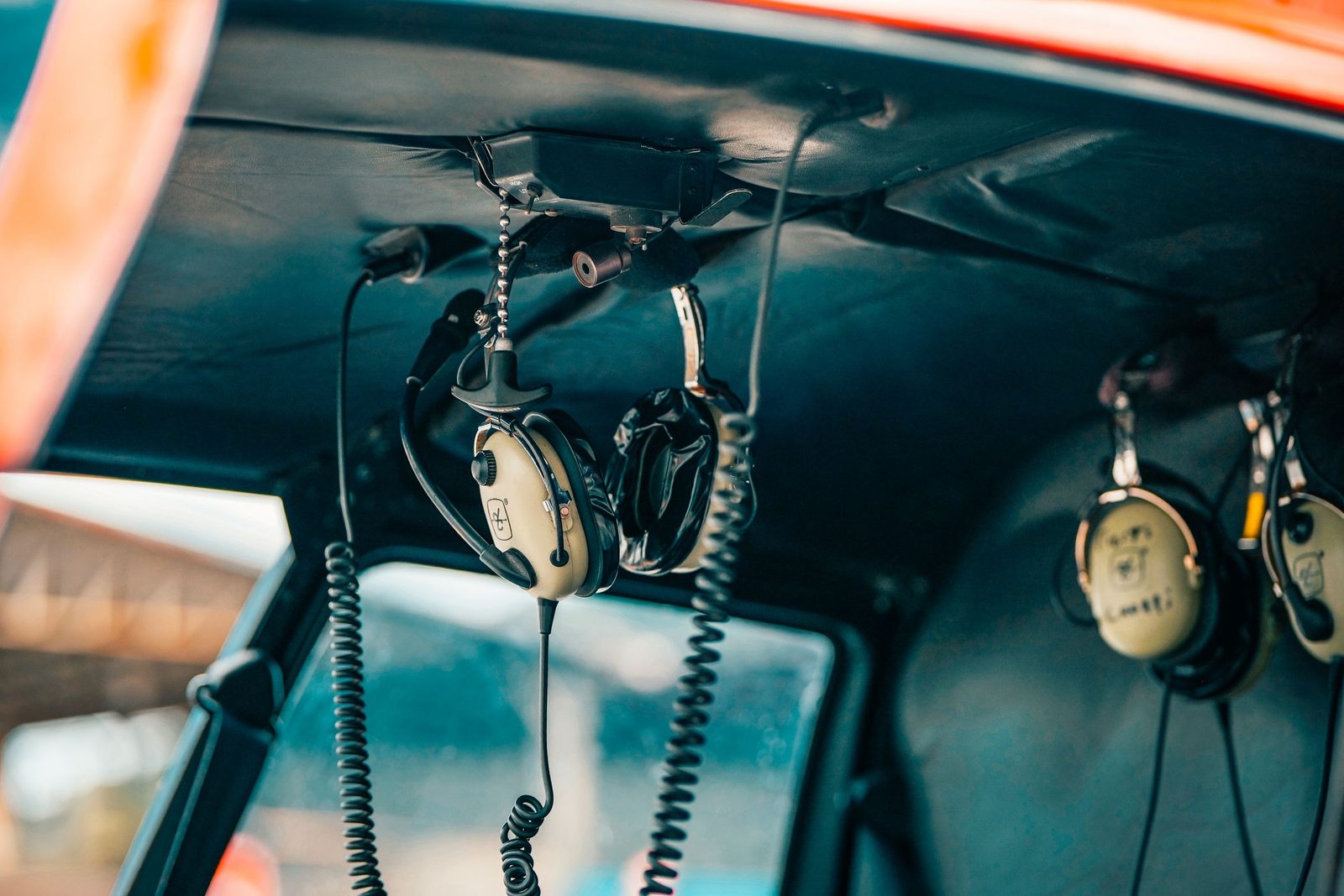 Aviation headsets hanging in an empty aircraft cockpit.