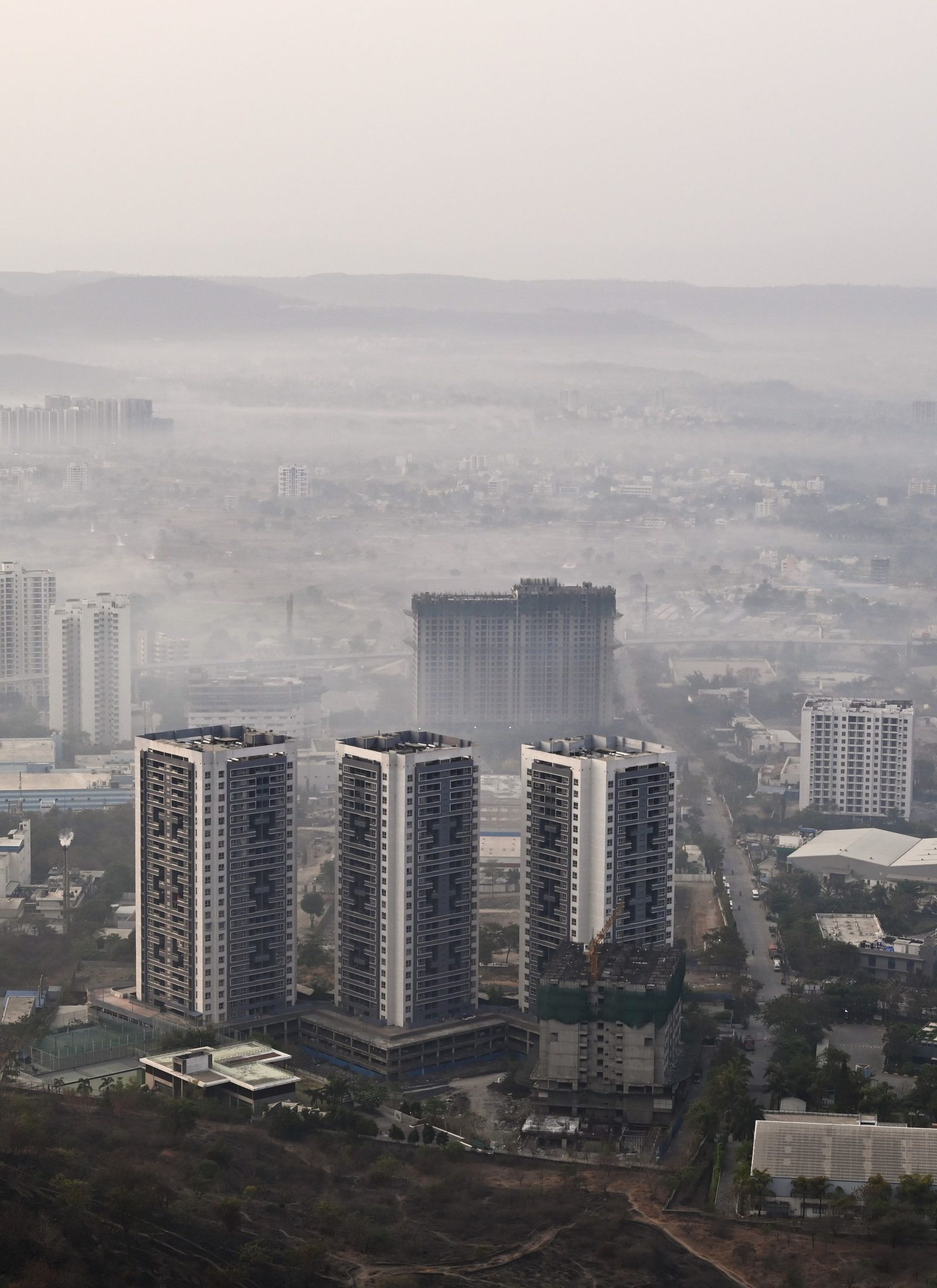 Pune’s apartment towers rising out of morning fog, seen from above.