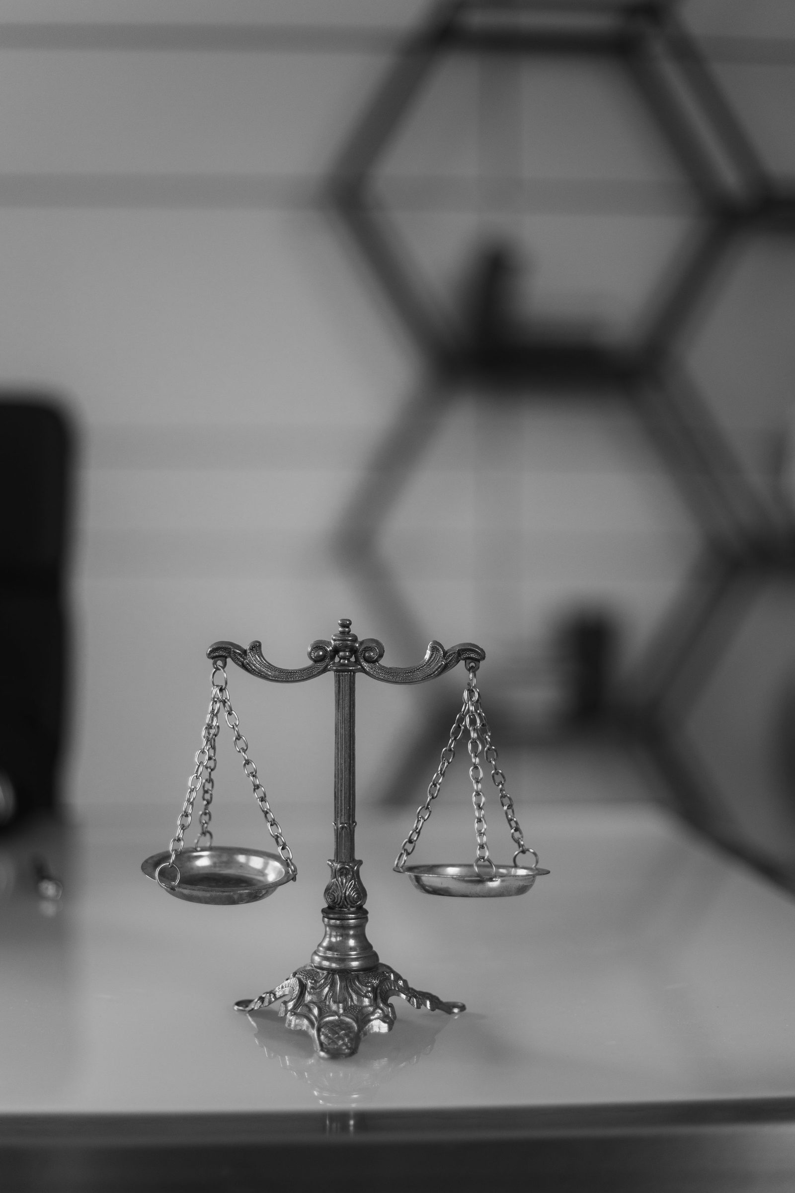 An old two-pan balance scale on a desk in black and white.