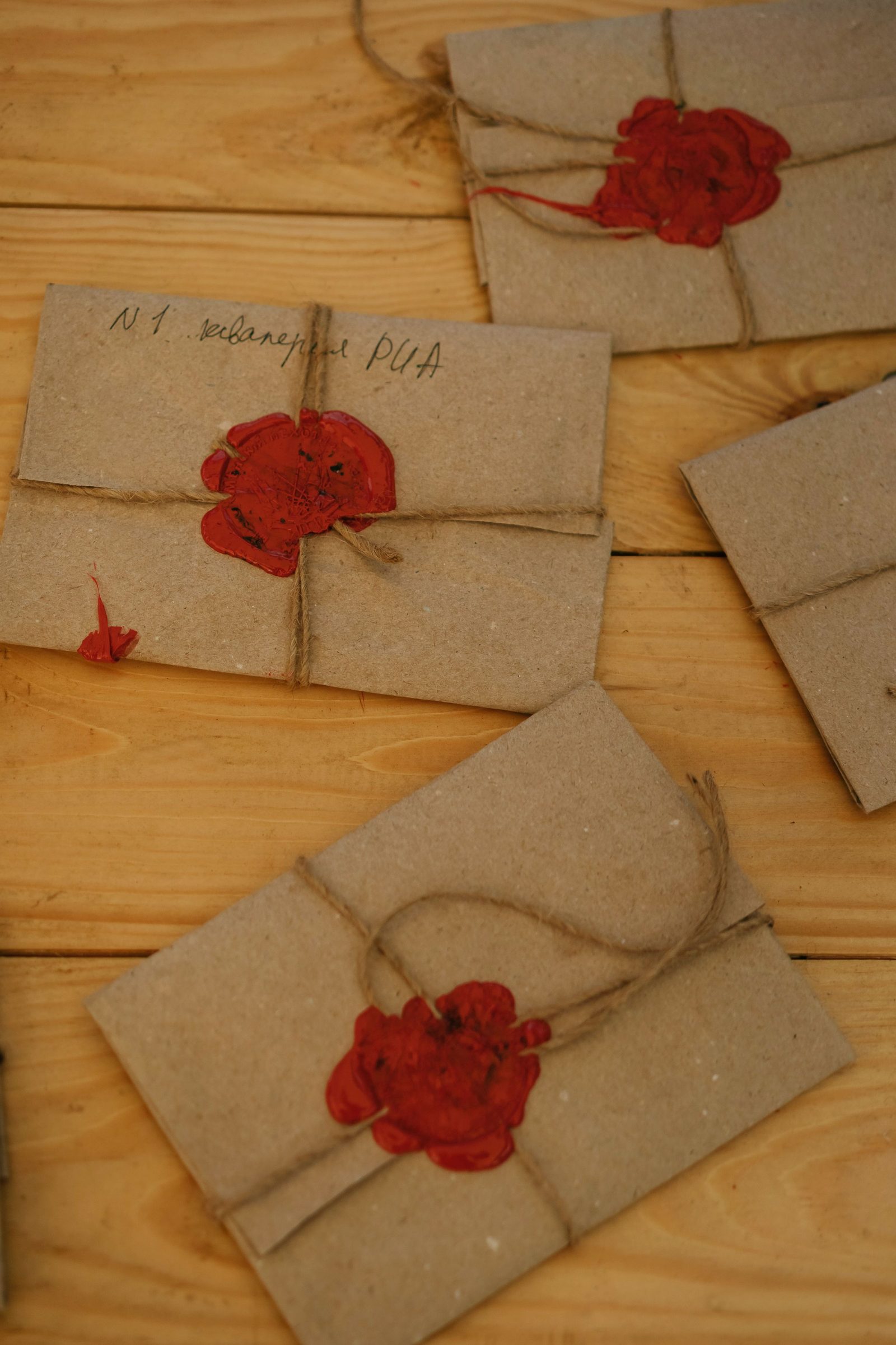 Recycled paper envelopes tied with string and sealed with red wax lie on a wooden table.
