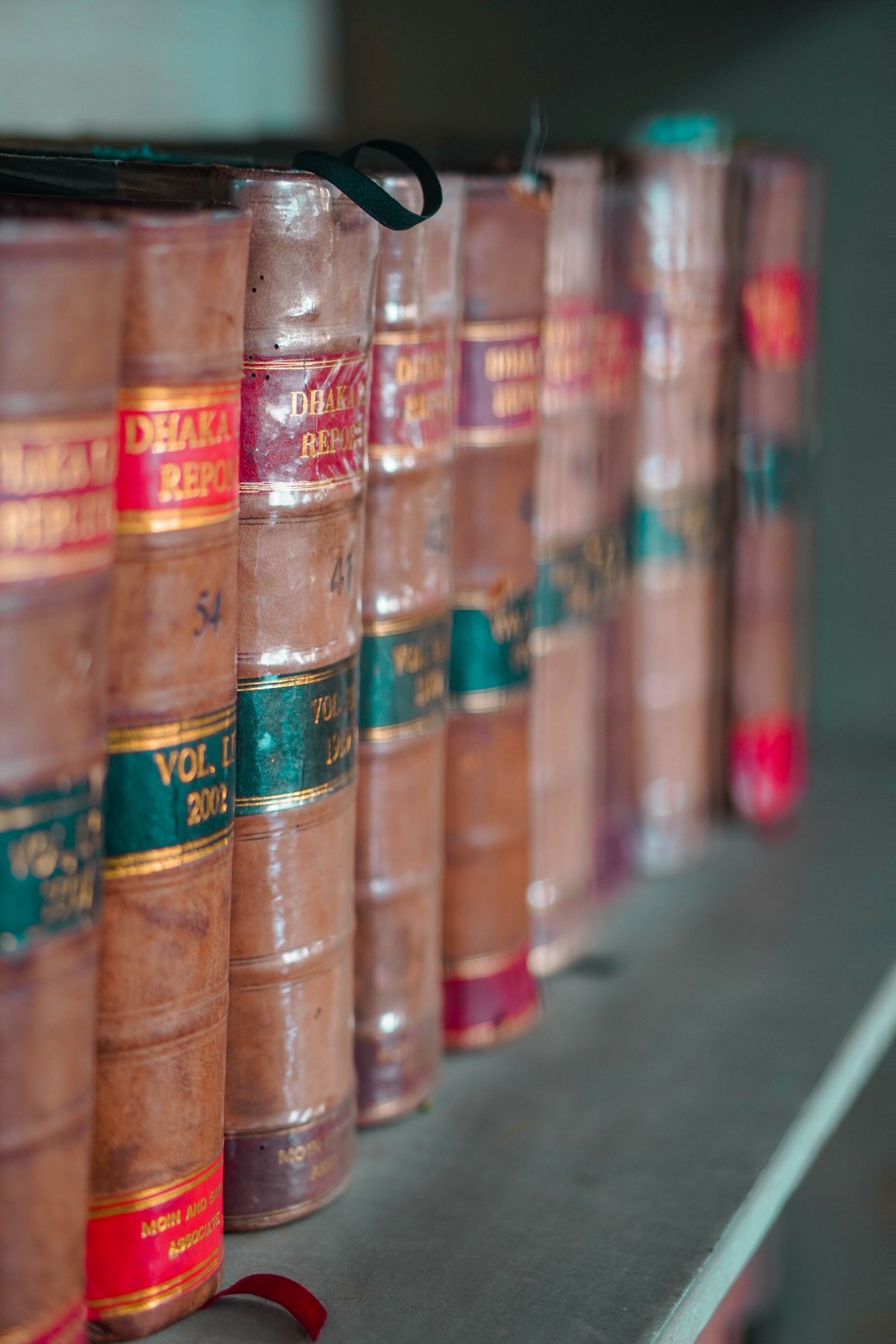 Leather-bound law books stacked on a wooden shelf.