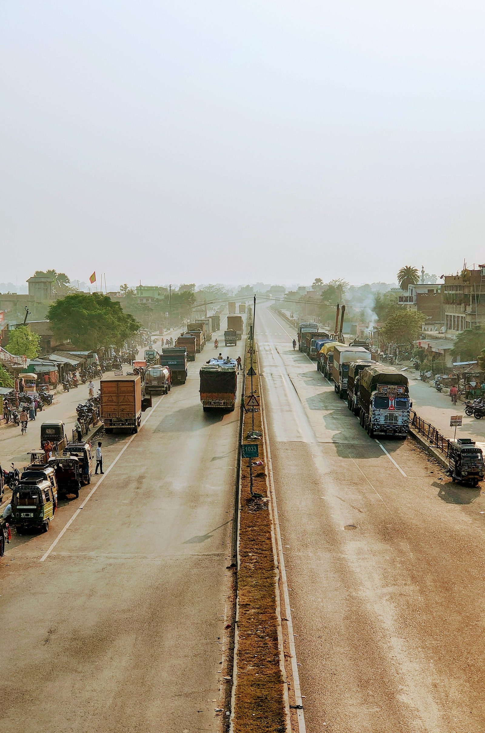 Trucks and buses crowd a highway at Piprakothi in Bihar under a pale sky.