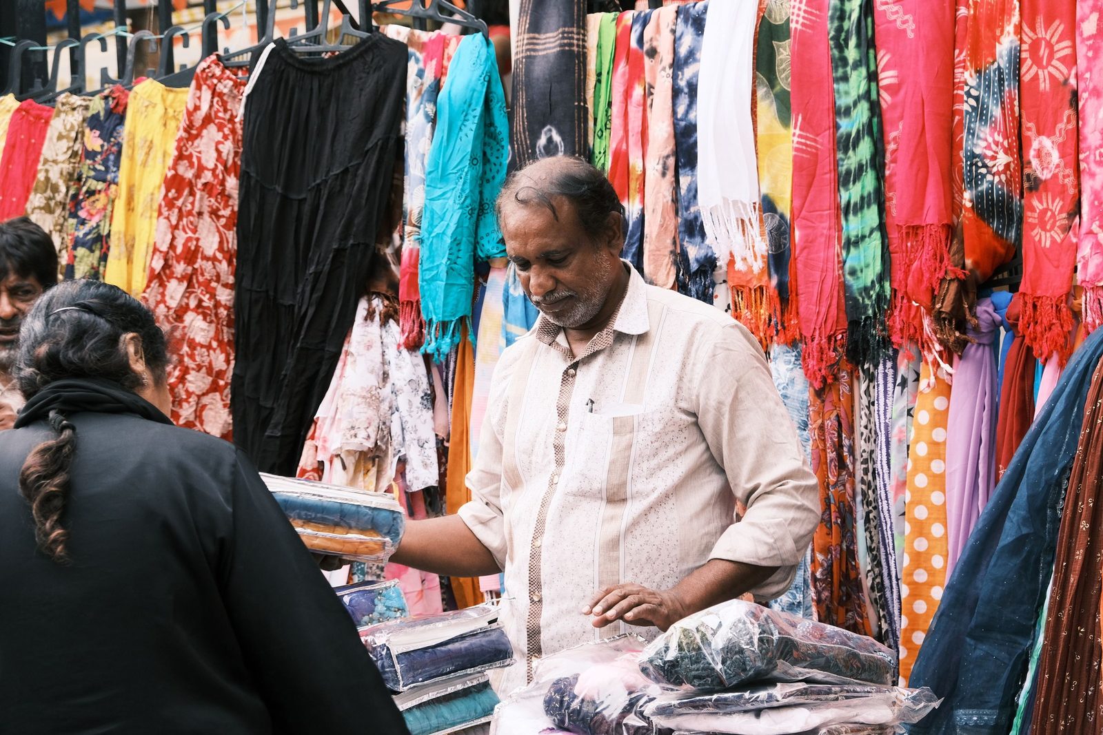 Vendors and customers talk among bright fabrics at a street market in Bengaluru.