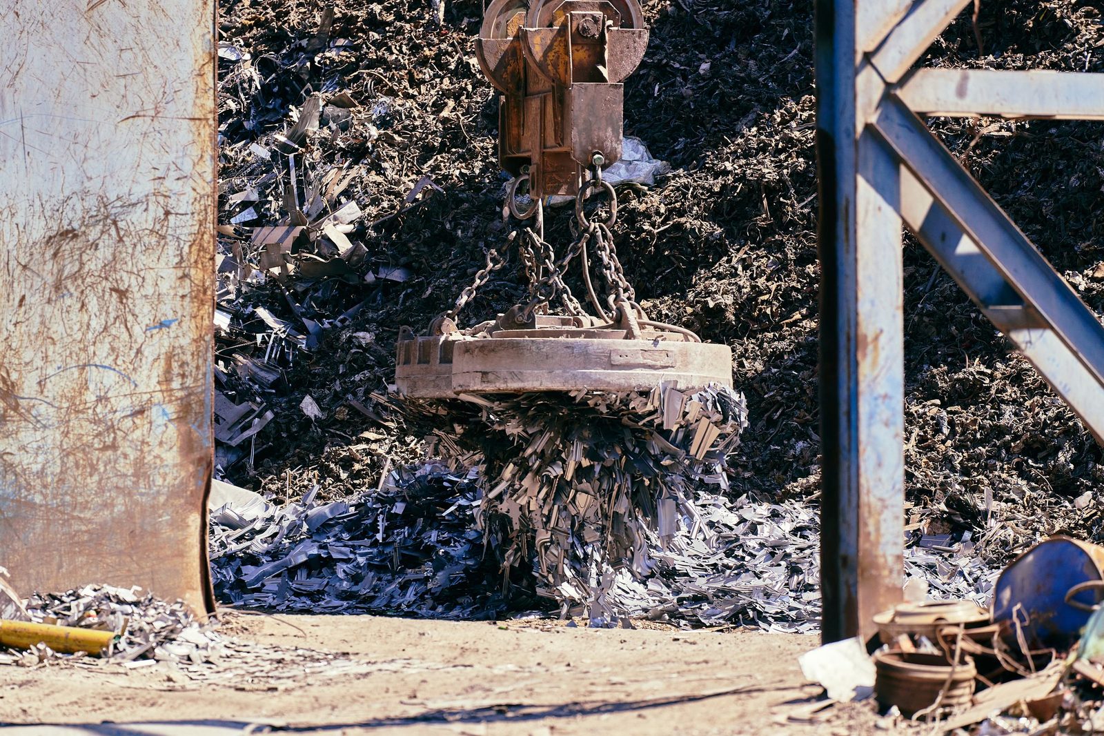 A magnet crane lifting scrap metal in a recycling yard.