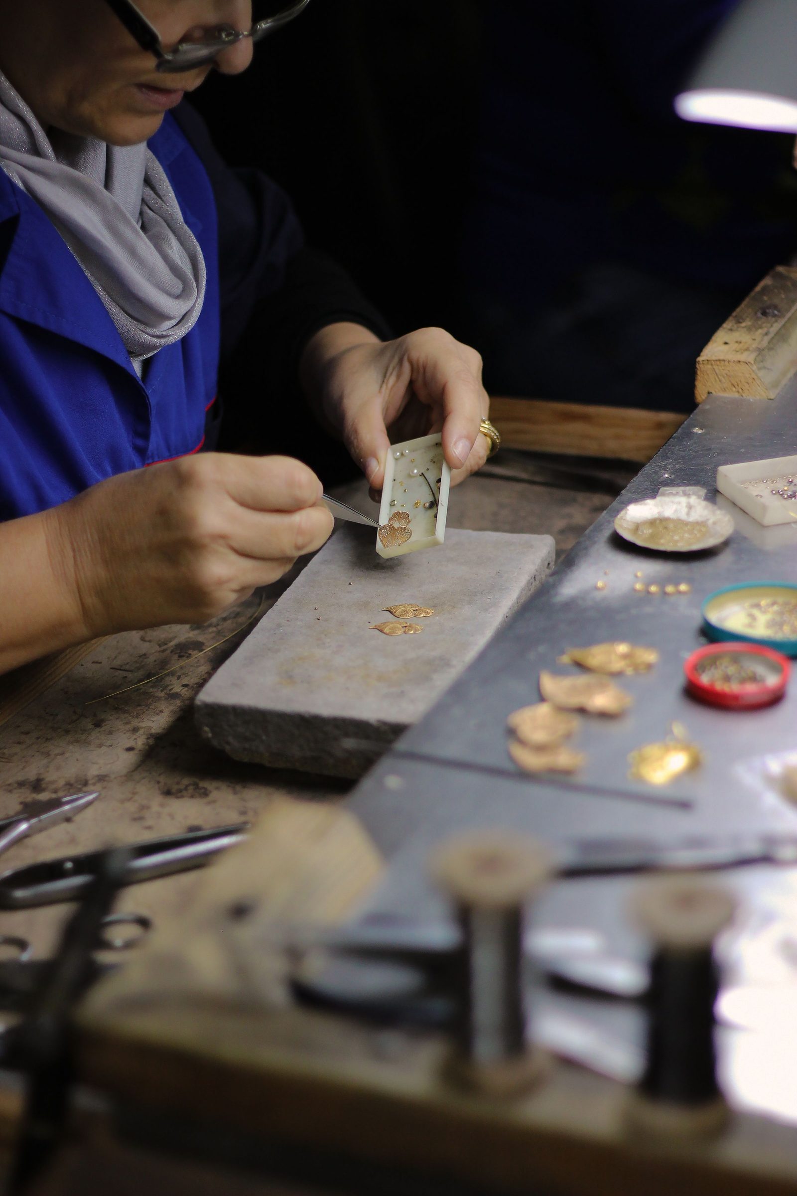 An artisan's hands shape a piece of gold jewellery at a workshop bench in Portugal.