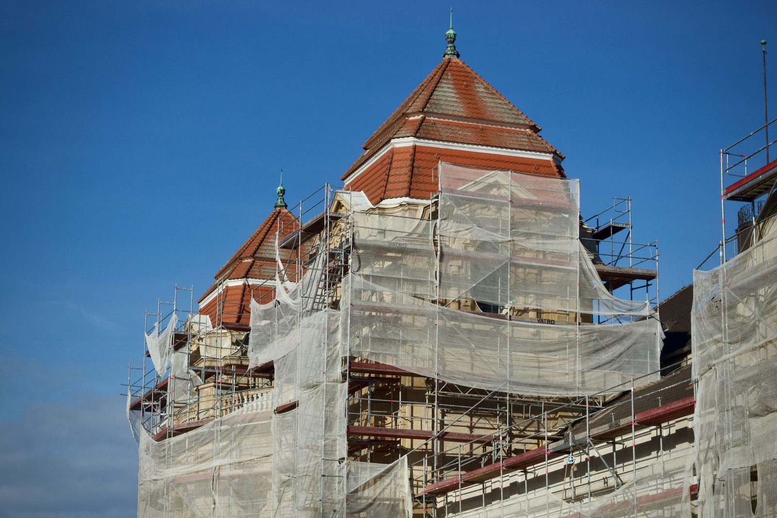 A historic building under restoration covered in scaffolding and protective netting.