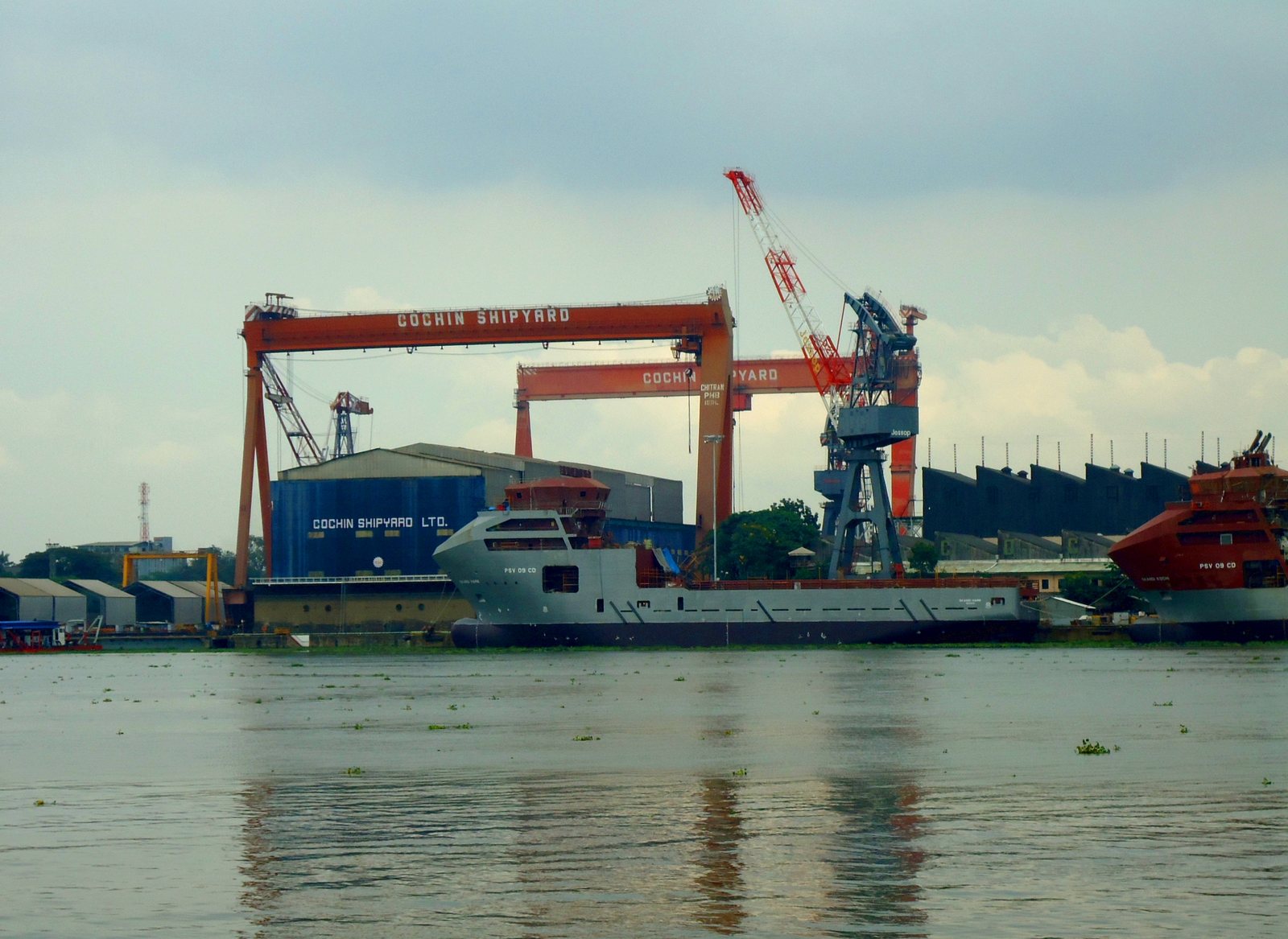 Tall yard cranes at Cochin Shipyard with an offshore supply vessel at the quay