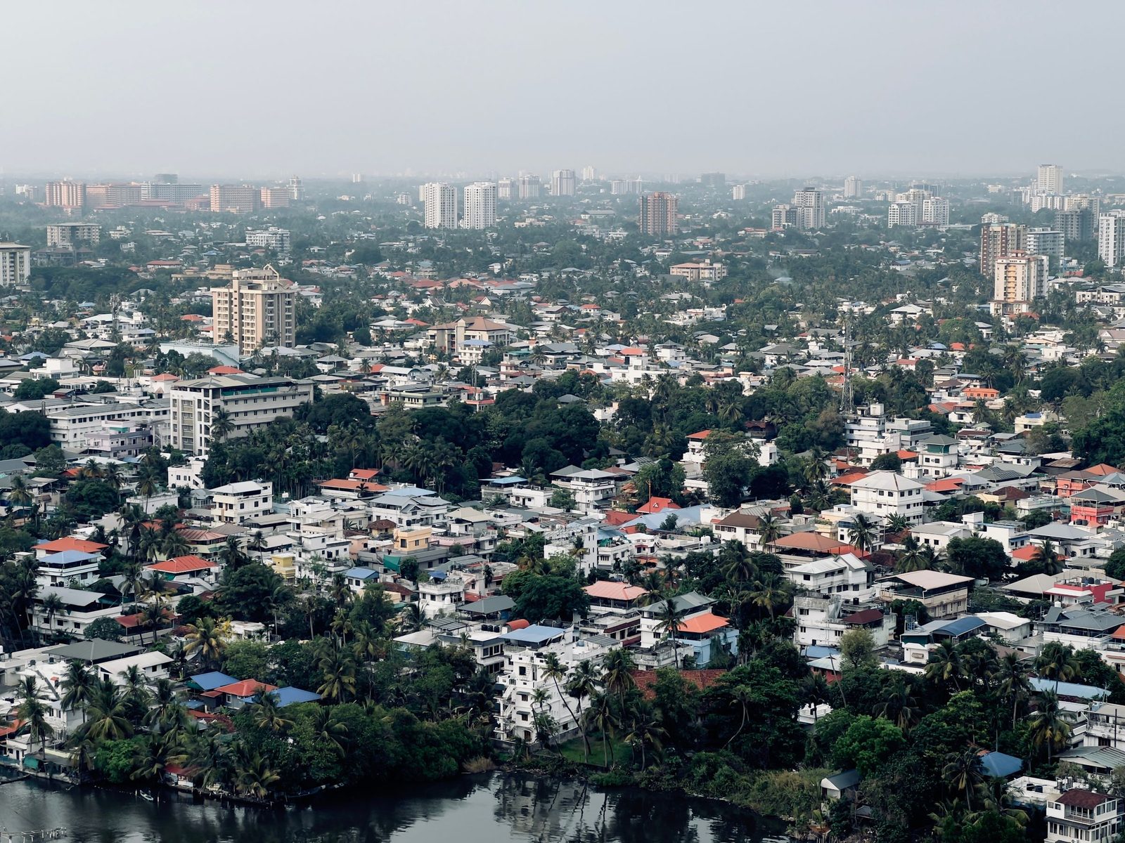 An aerial view of dense housing and a few high-rises among trees in Kochi.