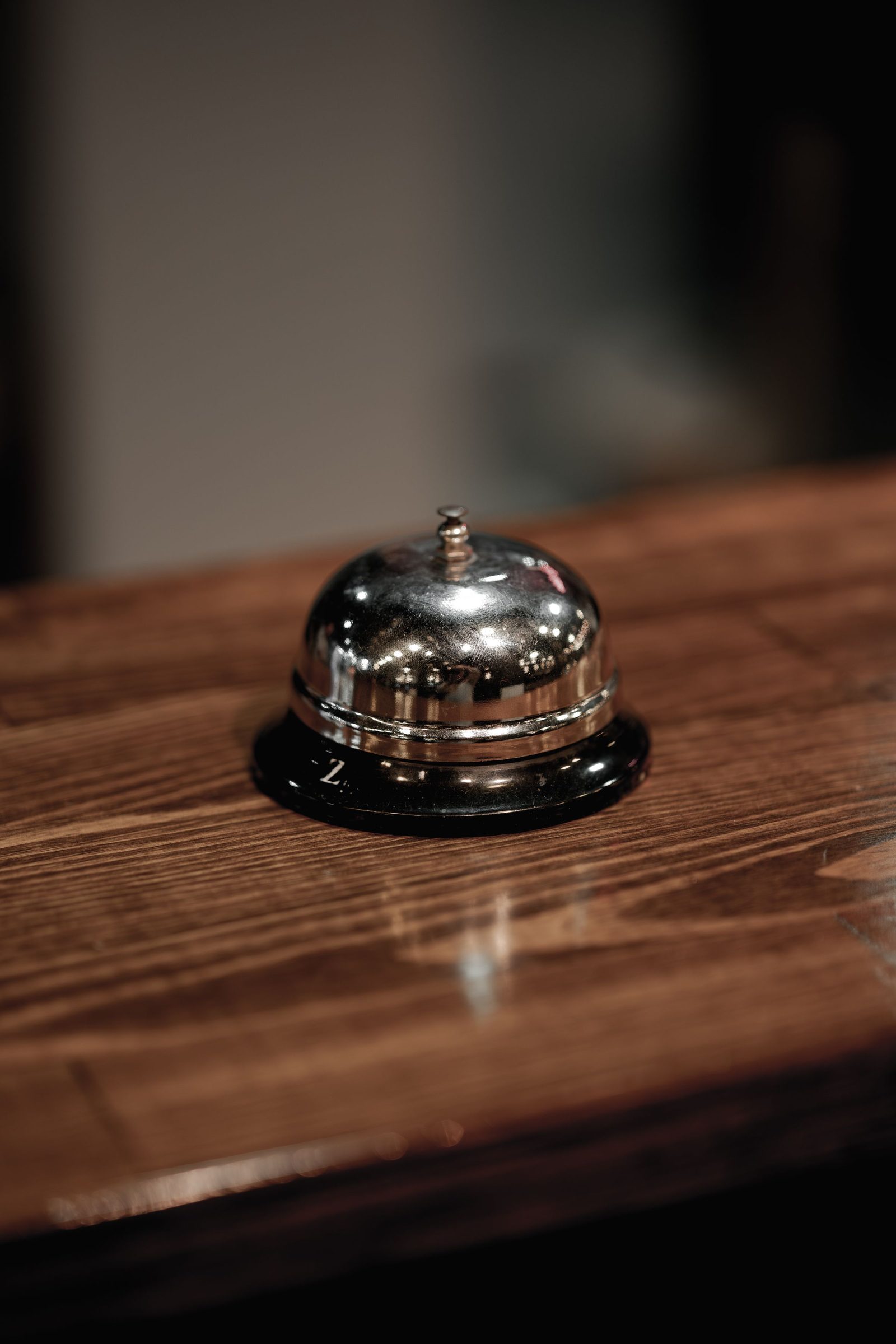 A polished metal service bell on a wooden counter.