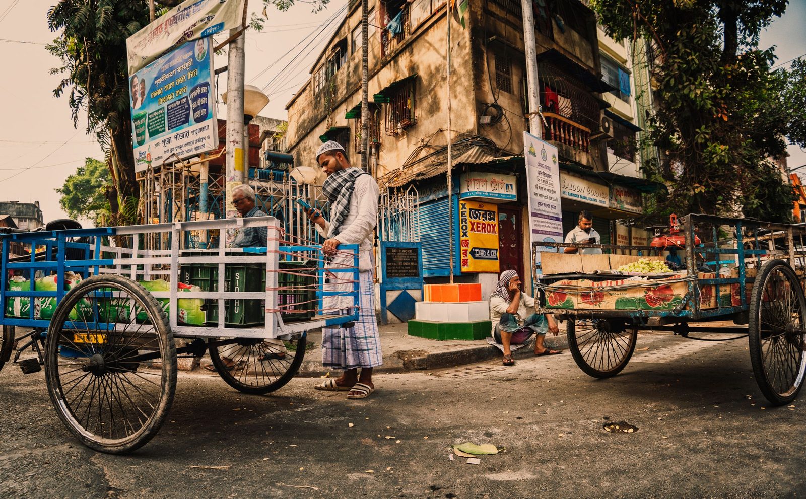 Men pull loaded hand carts along a busy street in Kolkata.