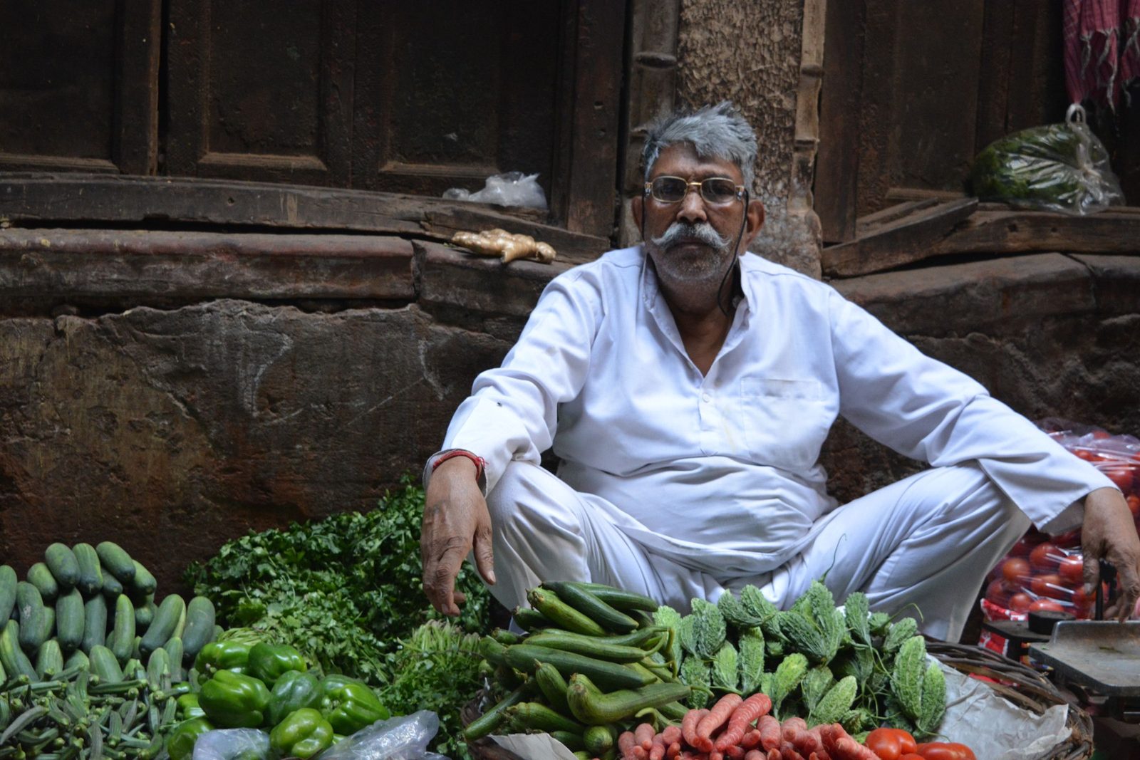 A vegetable seller sits among fresh produce in a market in Old Delhi.