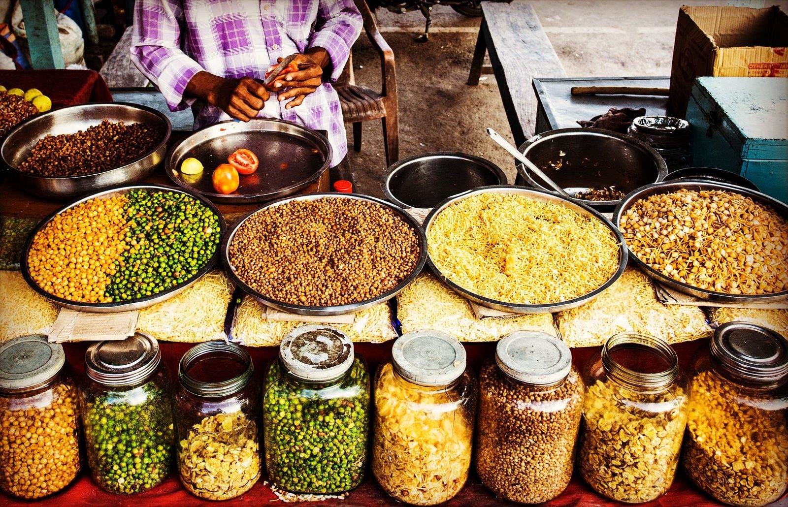 Glass jars of spices and lentils lined up at a market stall in India.