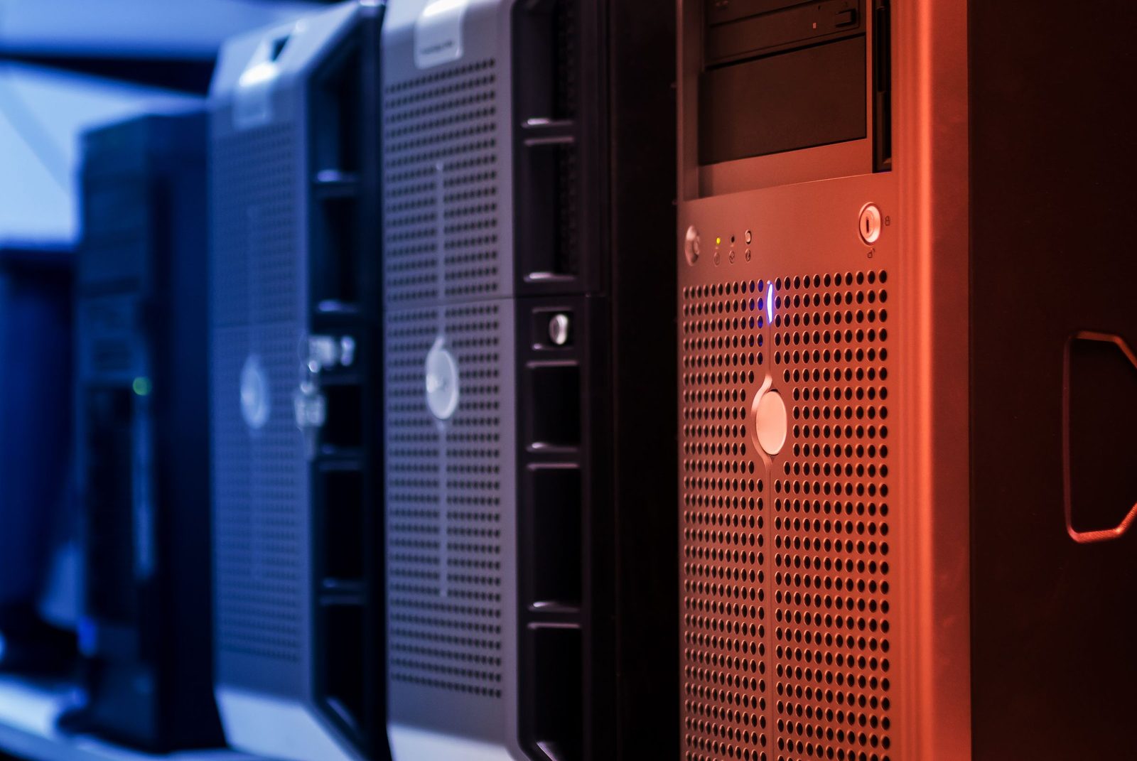A line of tower servers lit blue and red in a data centre.