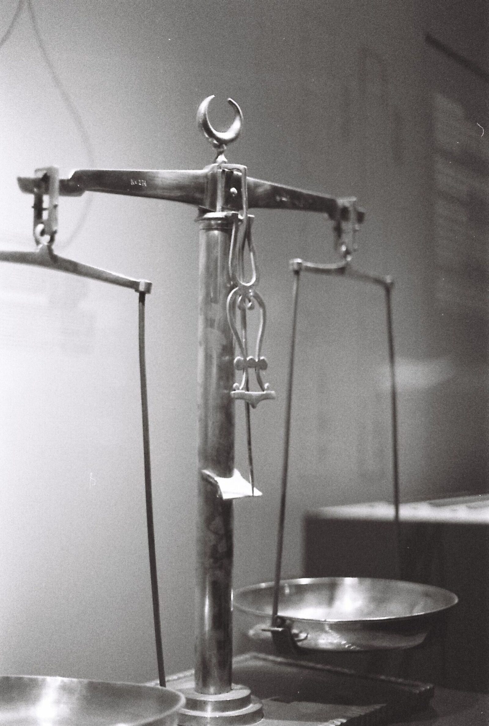A vintage balance scale stands in a museum display case in black and white.