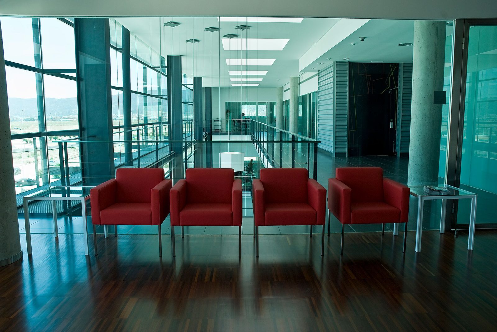 Bright red chairs in a modern office lobby lit by tall windows.