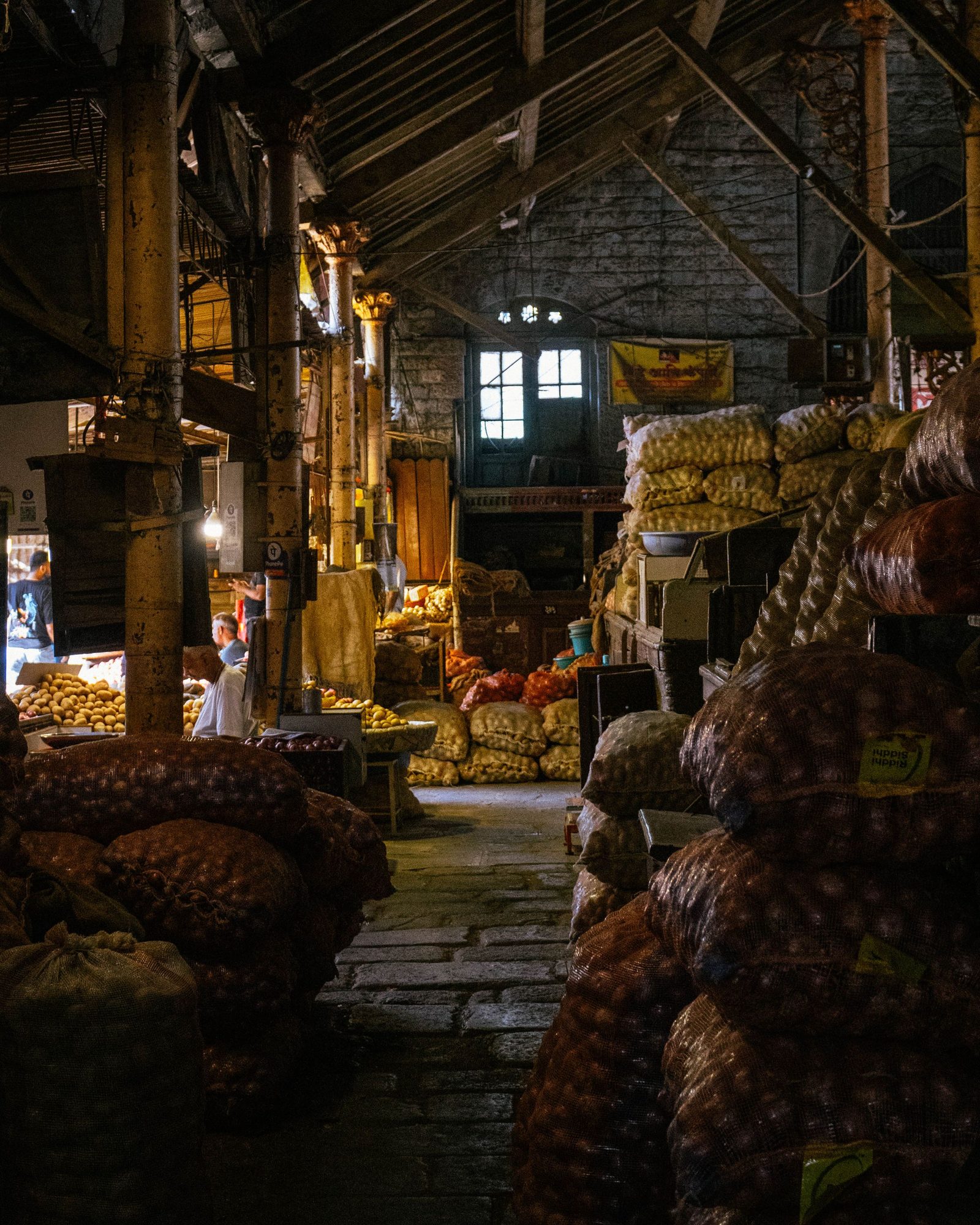 Stacks of onions and potatoes in sacks and baskets at a traditional Indian market.