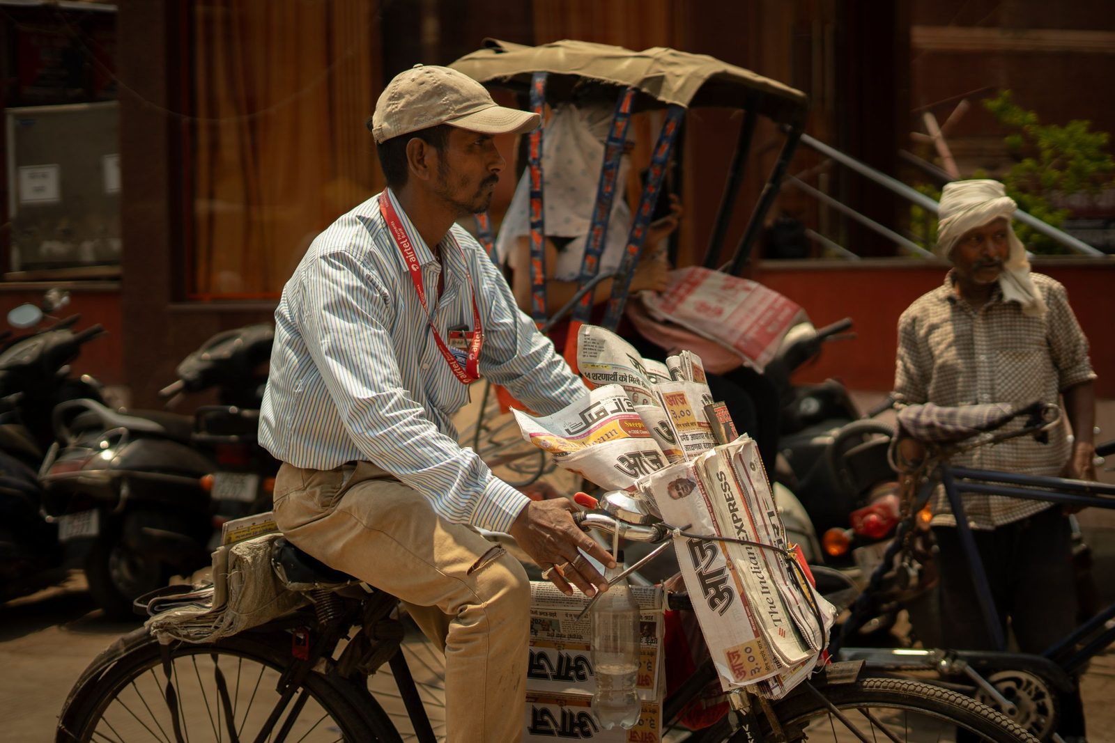 A newspaper vendor rides a bicycle loaded with papers through a street in Varanasi.