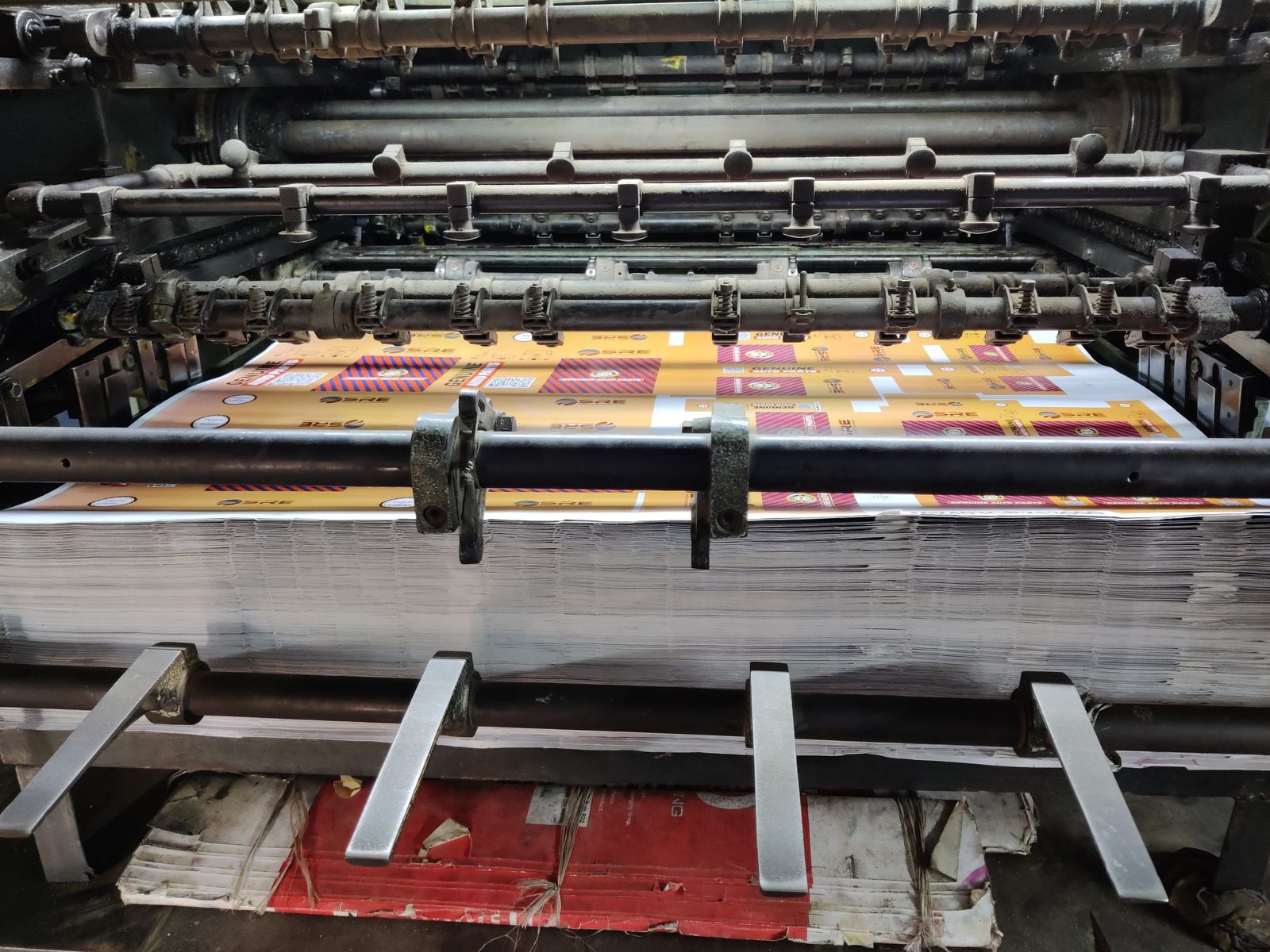 Sheets of paper feed through an industrial printing machine.
