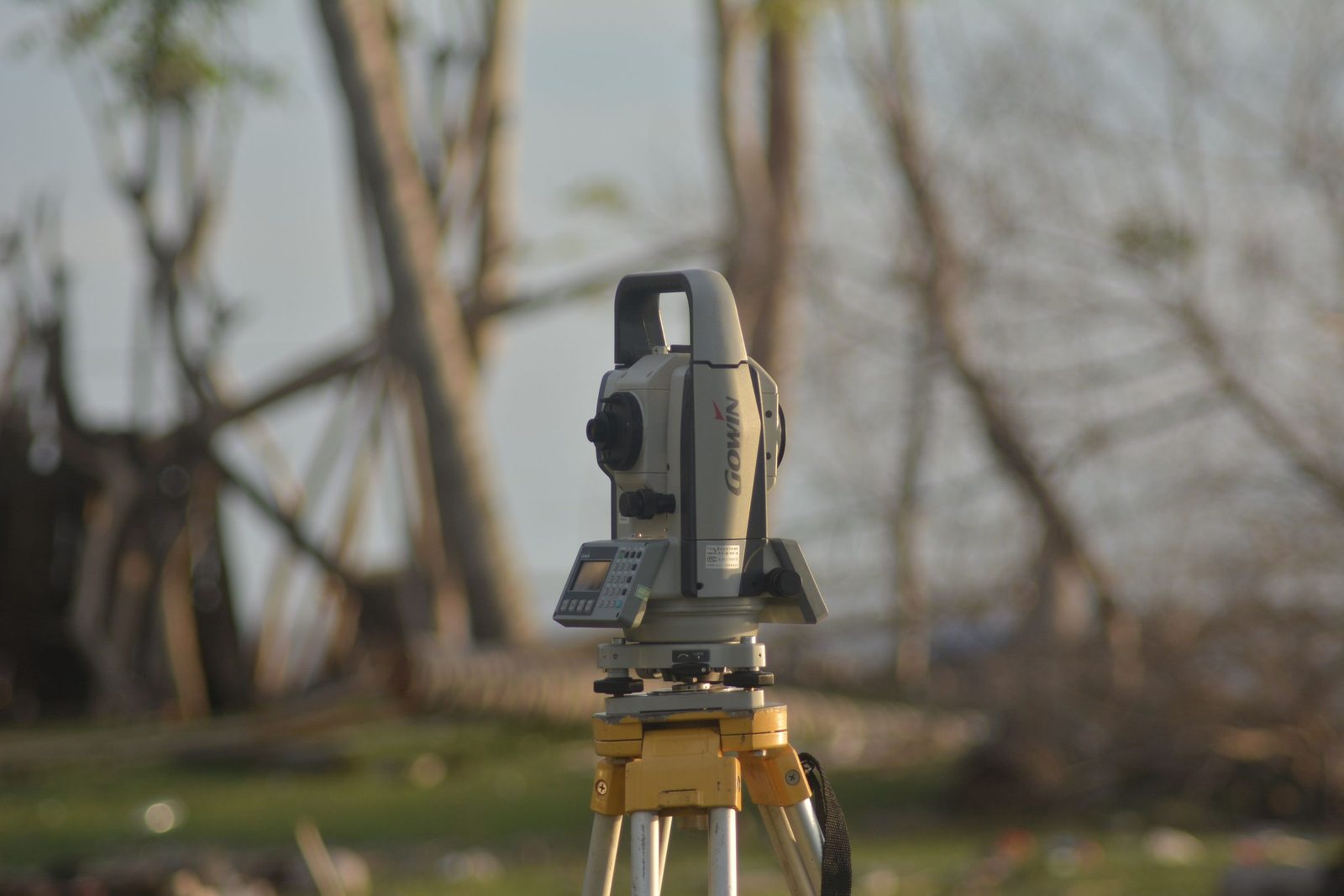 A surveying total station on a tripod at a construction site.