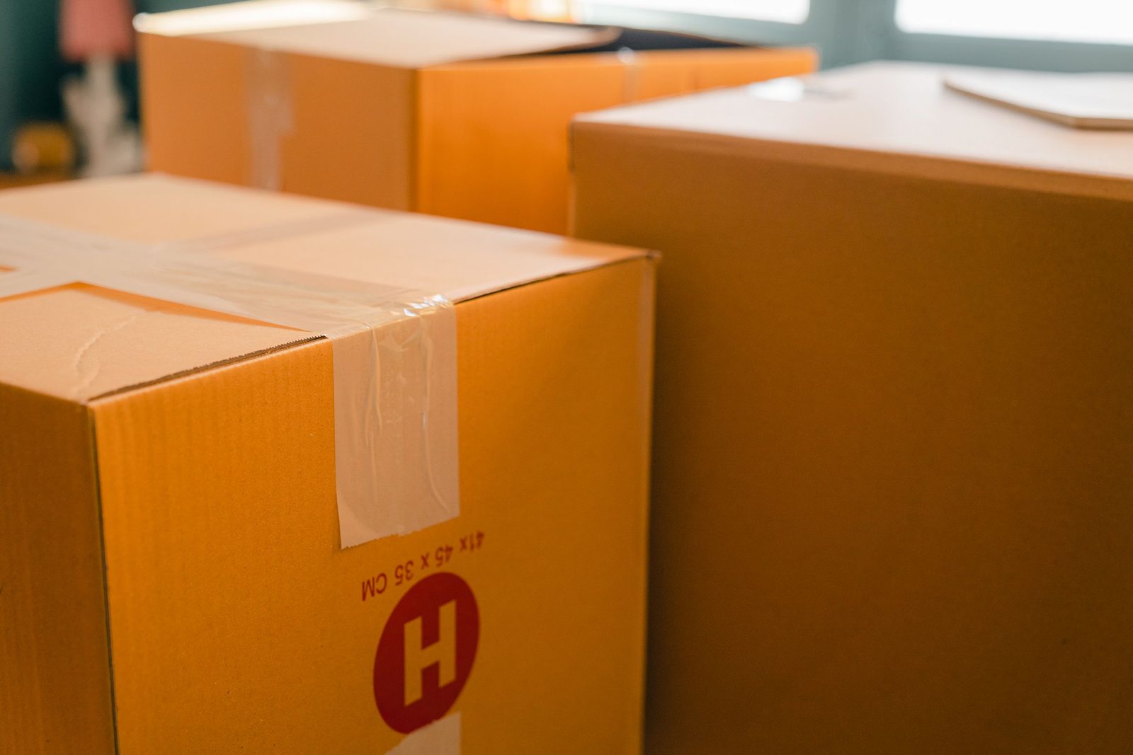 Taped cardboard boxes stacked by a sunlit window.