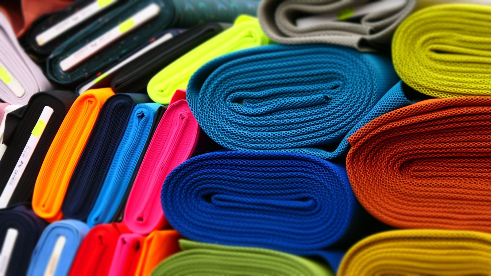 Rolls of brightly coloured fabric stacked on the shelves of a textile shop