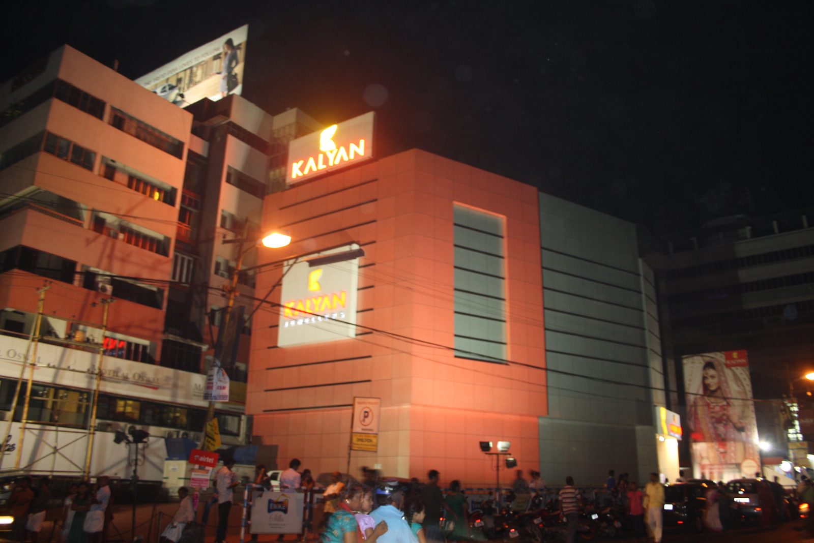 The Kalyan Jewellers showroom on the Round in Thrissur at night, its sign lit above a crowd on the street