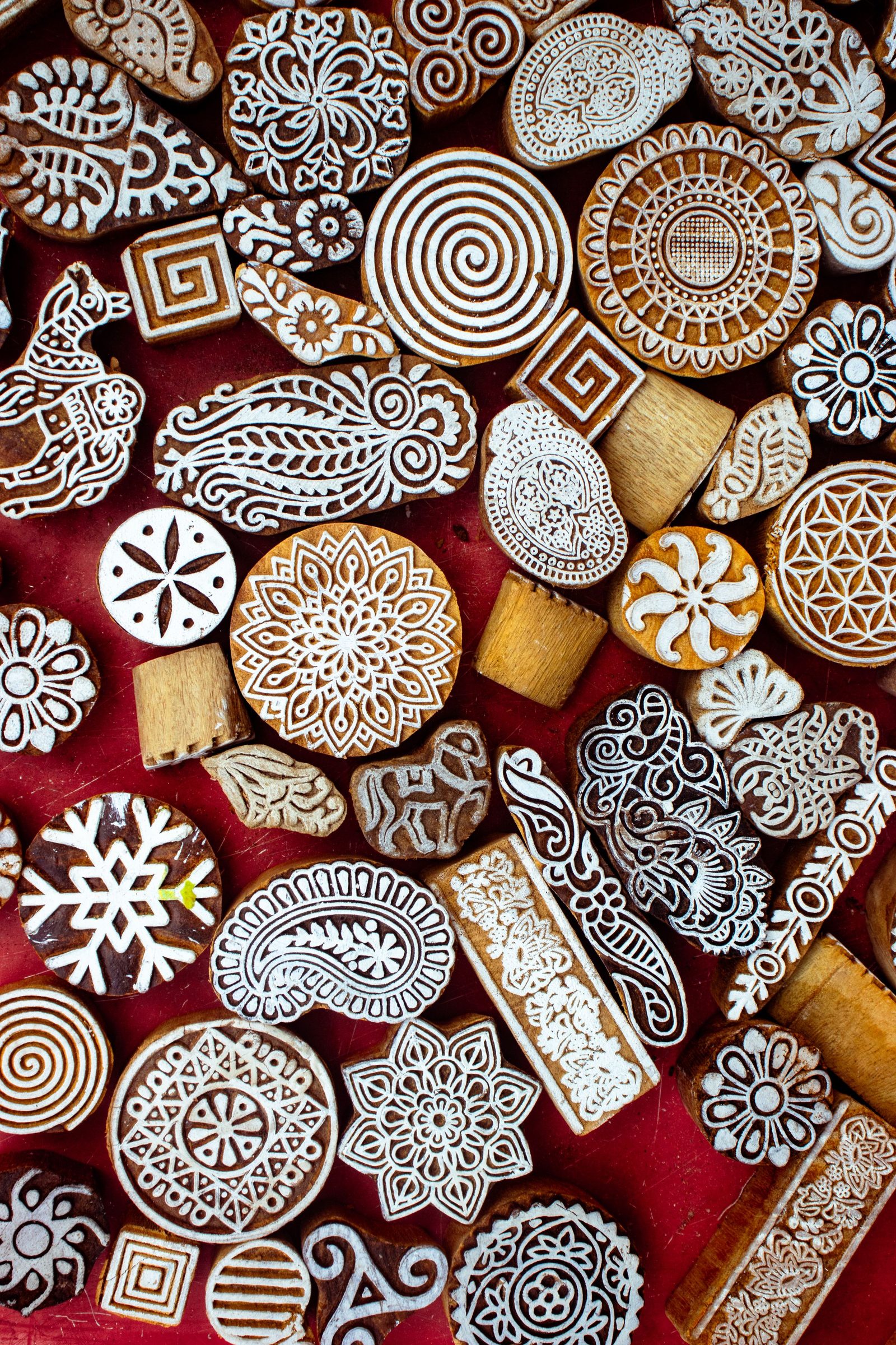 Carved wooden printing blocks with different ornate patterns are laid out on a red surface.