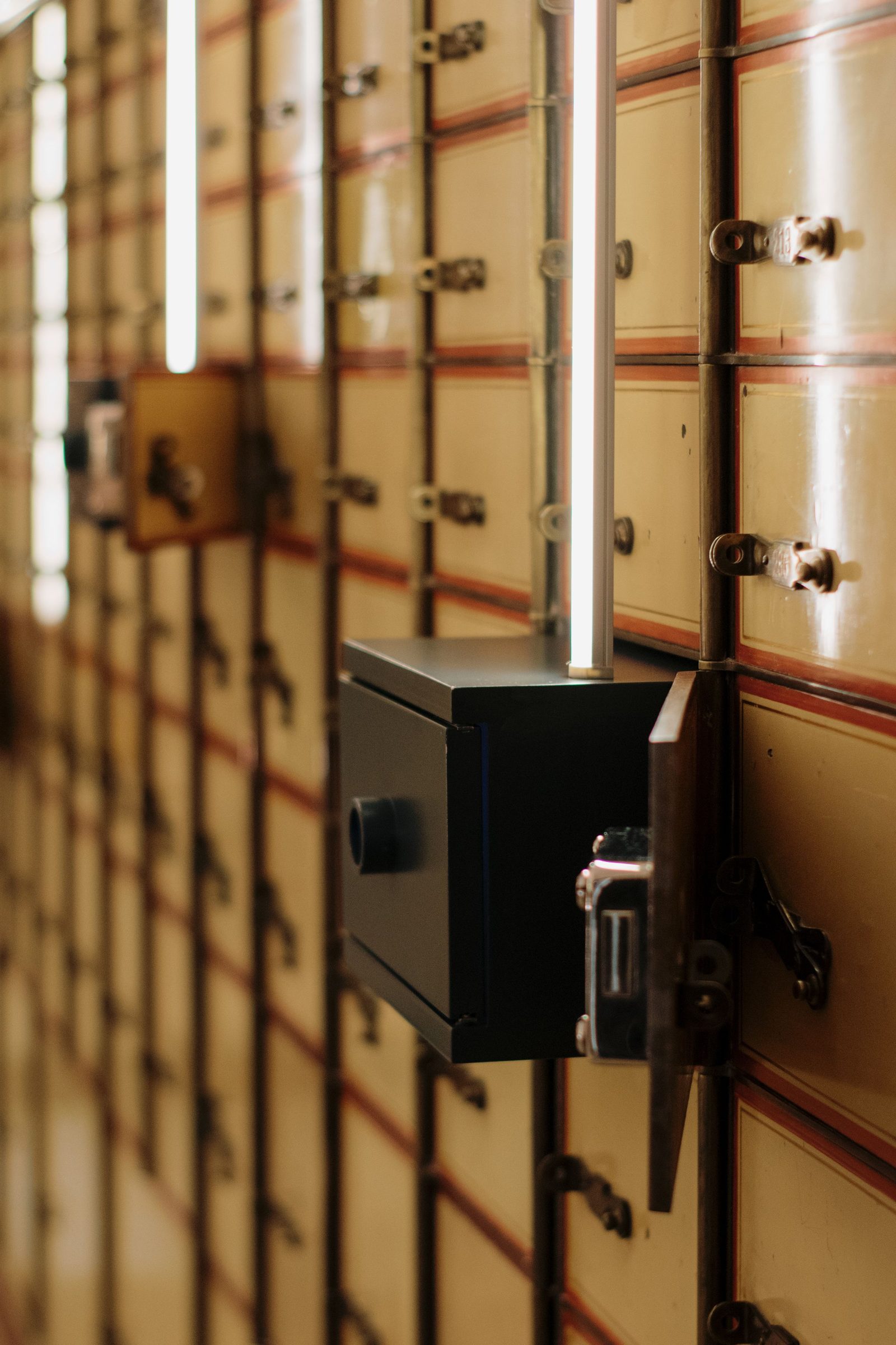 A wall of vintage safe deposit boxes with one door open.