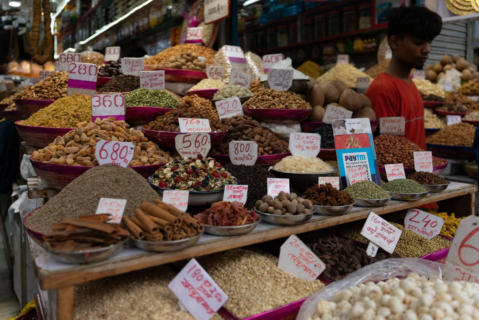 Spices and dry goods heaped in sacks and trays at a market stall in New Delhi.