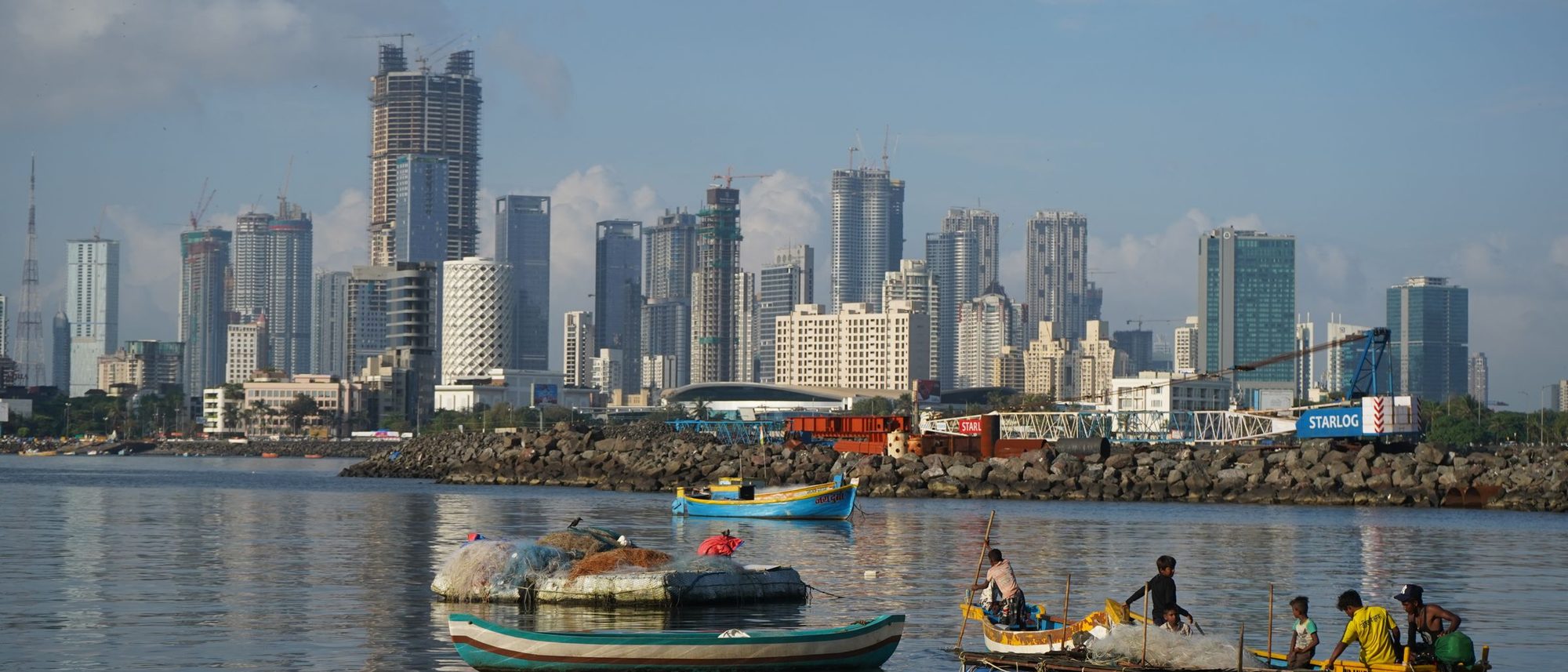 Fishing boats on the water in front of the Mumbai skyline.