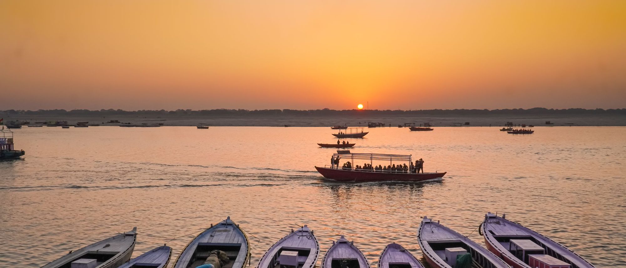 Wooden boats lined up along the Ganges at Varanasi at sunset.